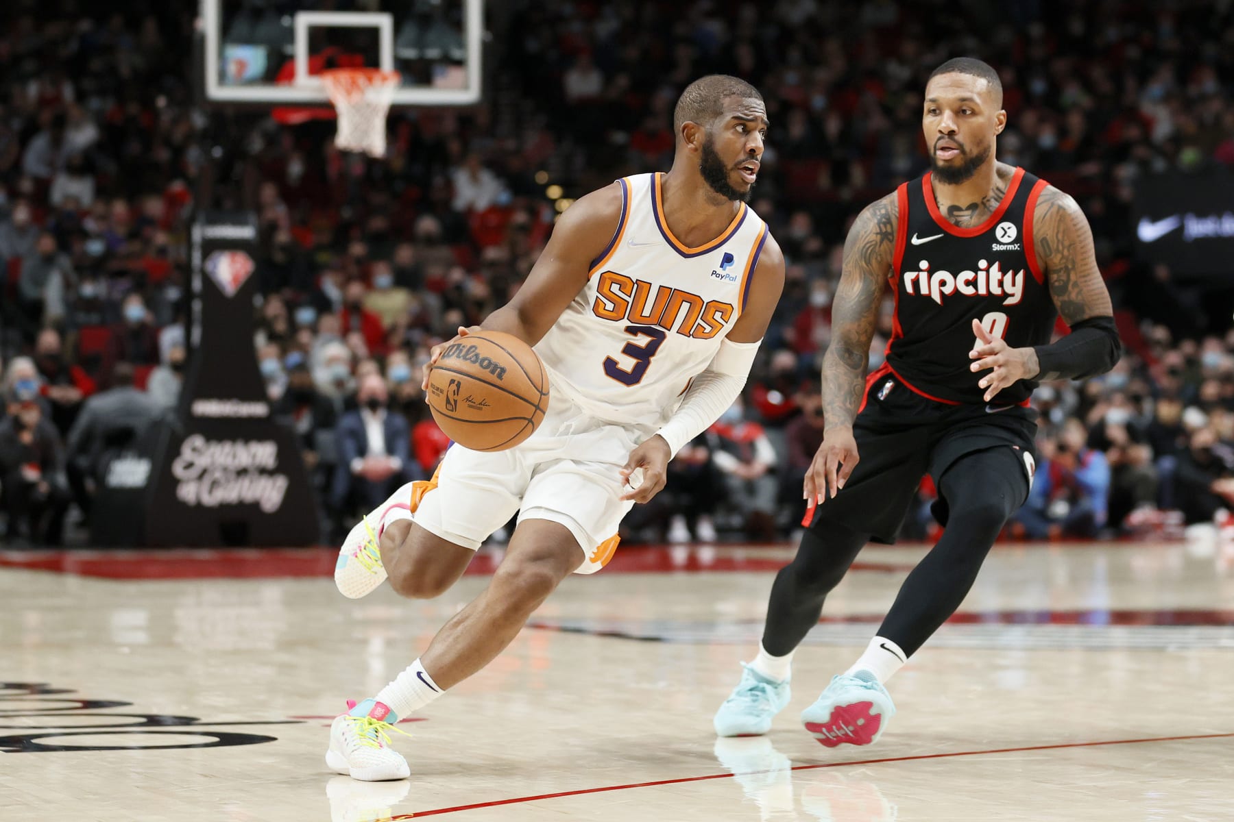 PORTLAND, OREGON - DECEMBER 14: Chris Paul #3 of the Phoenix Suns dribbles against Damian Lillard #0 of the Portland Trail Blazers during overtime at Moda Center on December 14, 2021 in Portland, Oregon. NOTE TO USER: User expressly acknowledges and agrees that, by downloading and or using this photograph, User is consenting to the terms and conditions of the Getty Images License Agreement. (Photo by Steph Chambers/Getty Images)
