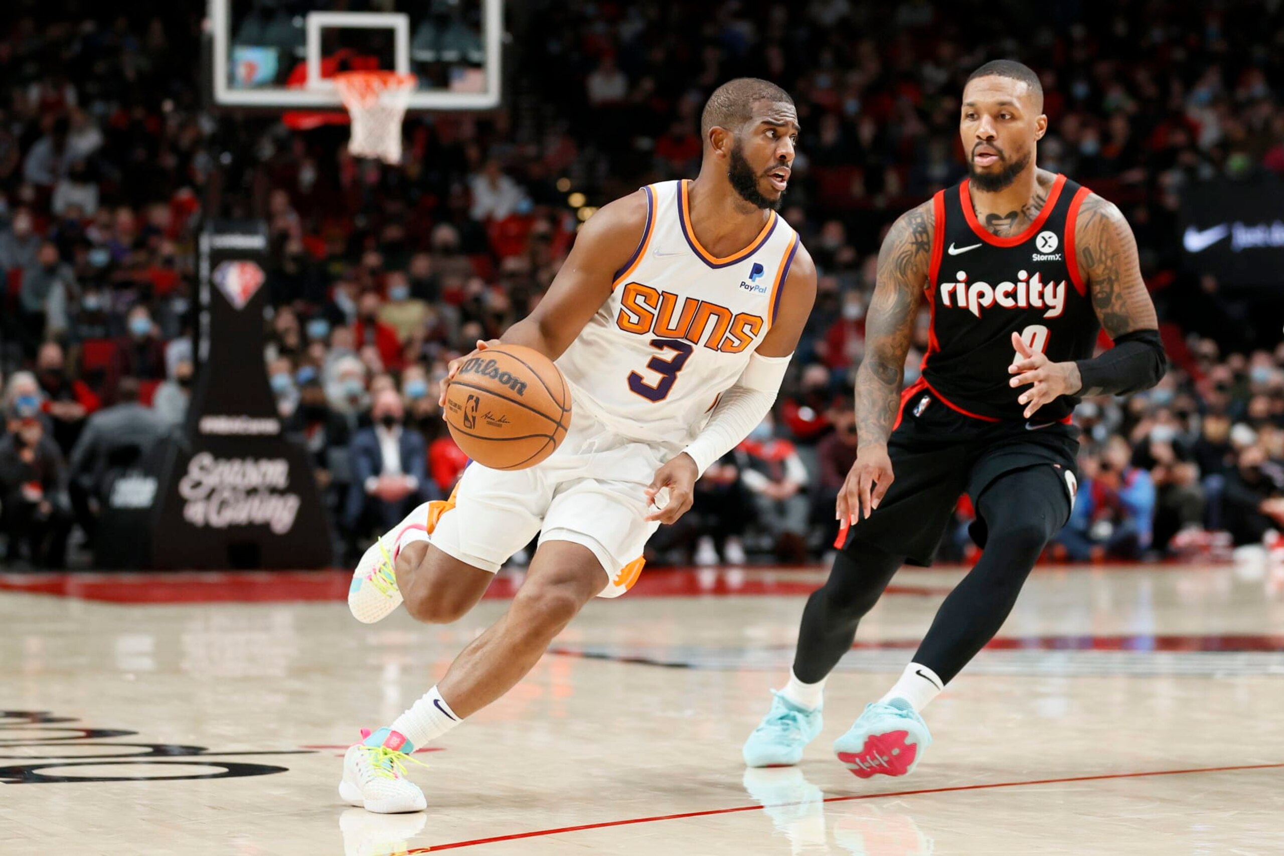 PORTLAND, OREGON - DECEMBER 14: Chris Paul #3 of the Phoenix Suns dribbles against Damian Lillard #0 of the Portland Trail Blazers during overtime at Moda Center on December 14, 2021 in Portland, Oregon. NOTE TO USER: User expressly acknowledges and agrees that, by downloading and or using this photograph, User is consenting to the terms and conditions of the Getty Images License Agreement. (Photo by Steph Chambers/Getty Images)
