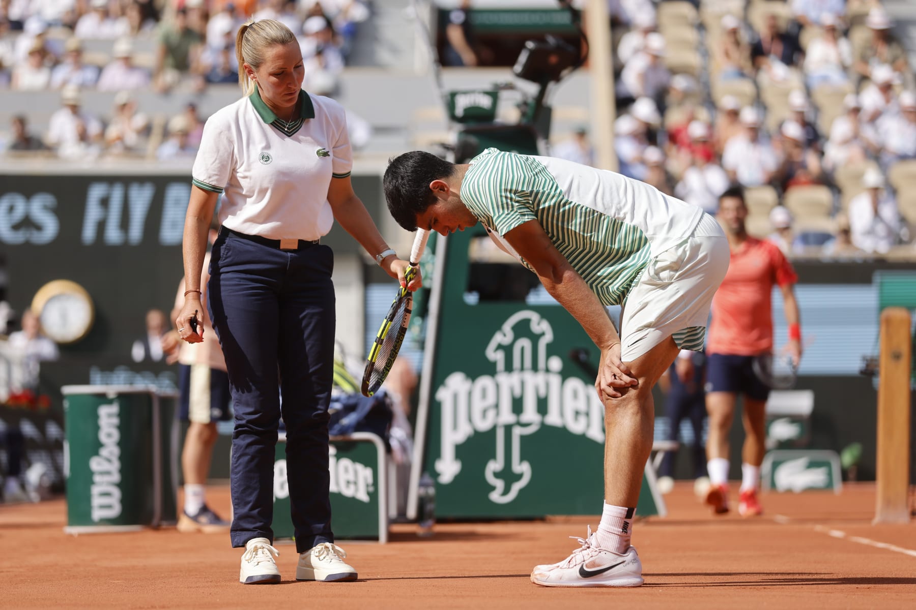 Spain's Carlos Alcaraz, right, speaks with chair umpire Aurelie Tourte of France as he reacts with pain at the end of the third game of the third set during his semifinal match of the French Open tennis tournament against Serbia's Novak Djokovic at the Roland Garros stadium in Paris, Friday, June 9, 2023. (AP Photo/Jean-Francois Badias)