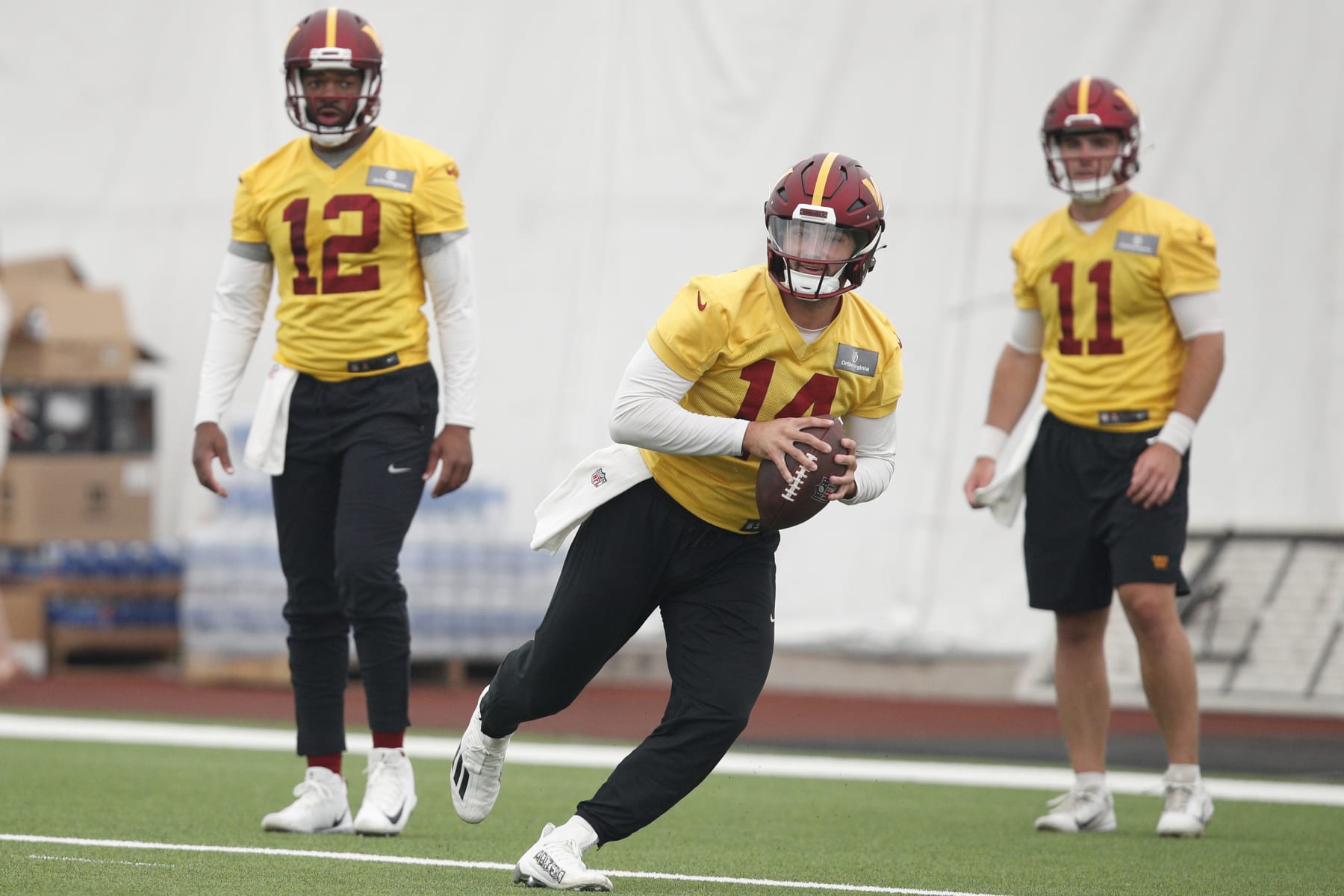 Washington Commanders quarterback Sam Howell (14) scrambles as quarterbacks Jacoby Brissett (12) and Jake Fromm (11) look on during an NFL football practice at the team's indoor training facility in Ashburn, Va., Thursday, June 8, 2023. (AP Photo/Luis M. Alvarez)