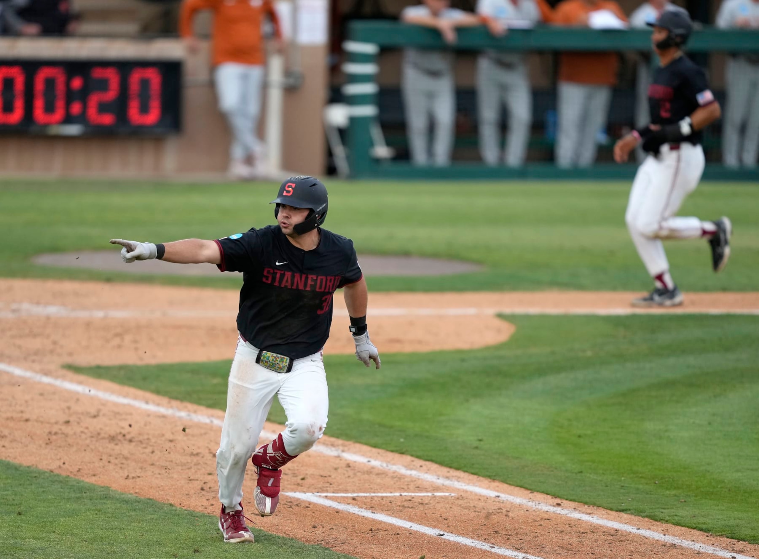 Stanford's Carter Graham, left, points to the dugout after hitting a single to drive in a run against Texas in the fourth inning of an NCAA college baseball tournament super regional game in Stanford, Calif., Monday, June 12, 2023. (AP Photo/Tony Avelar)
