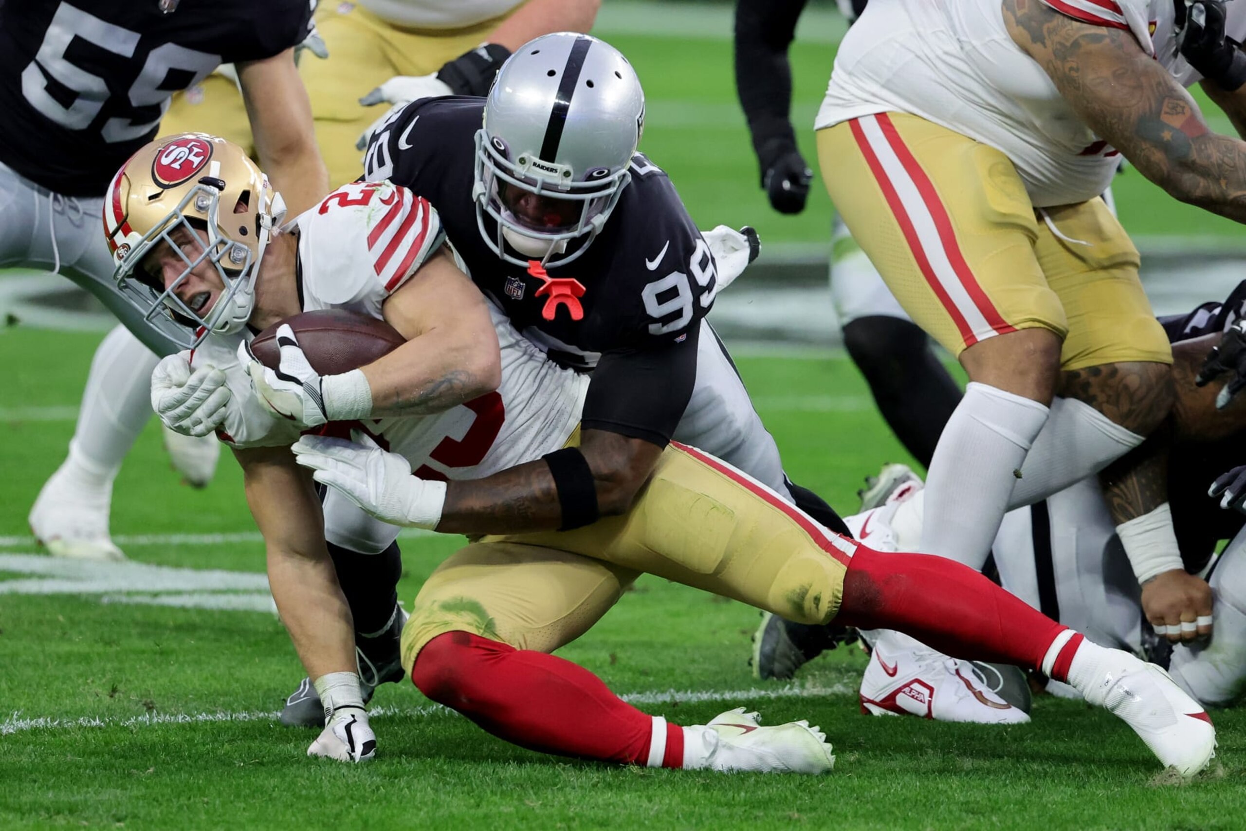 LAS VEGAS, NEVADA - JANUARY 01: Christian McCaffrey #23 of the San Francisco 49ers is tackled by Clelin Ferrell #99 of the Las Vegas Raiders during the first quarter at Allegiant Stadium on January 01, 2023 in Las Vegas, Nevada. (Photo by Ethan Miller/Getty Images)
