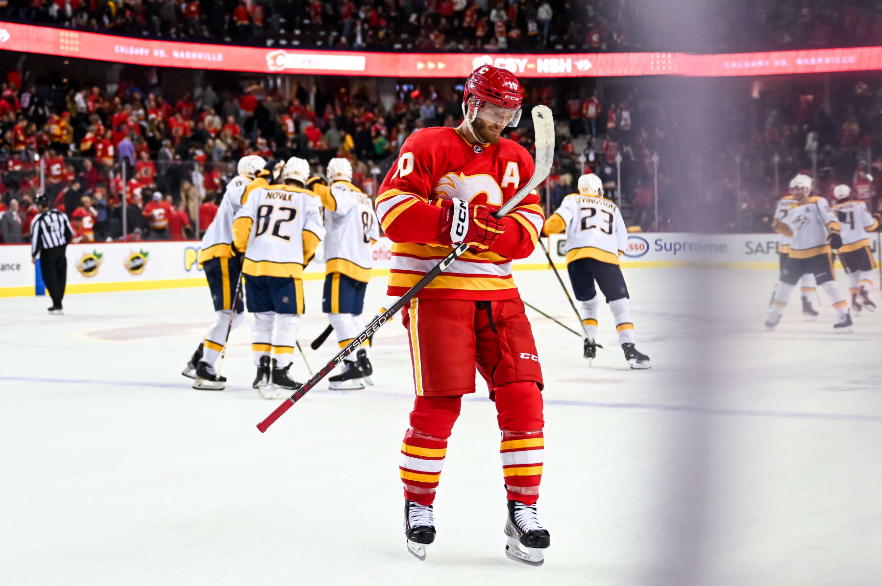 CALGARY, AB - APRIL 10: Nashville Predators Center Tommy Novak (82) celebrates with teammates after scoring the game-winning goal during the shootout while Calgary Flames Left Wing Jonathan Huberdeau (10) looks on after an NHL game on April 10, 2023, at the Scotiabank Saddledome in Calgary, AB. (Photo by Brett Holmes/Icon Sportswire via Getty Images)