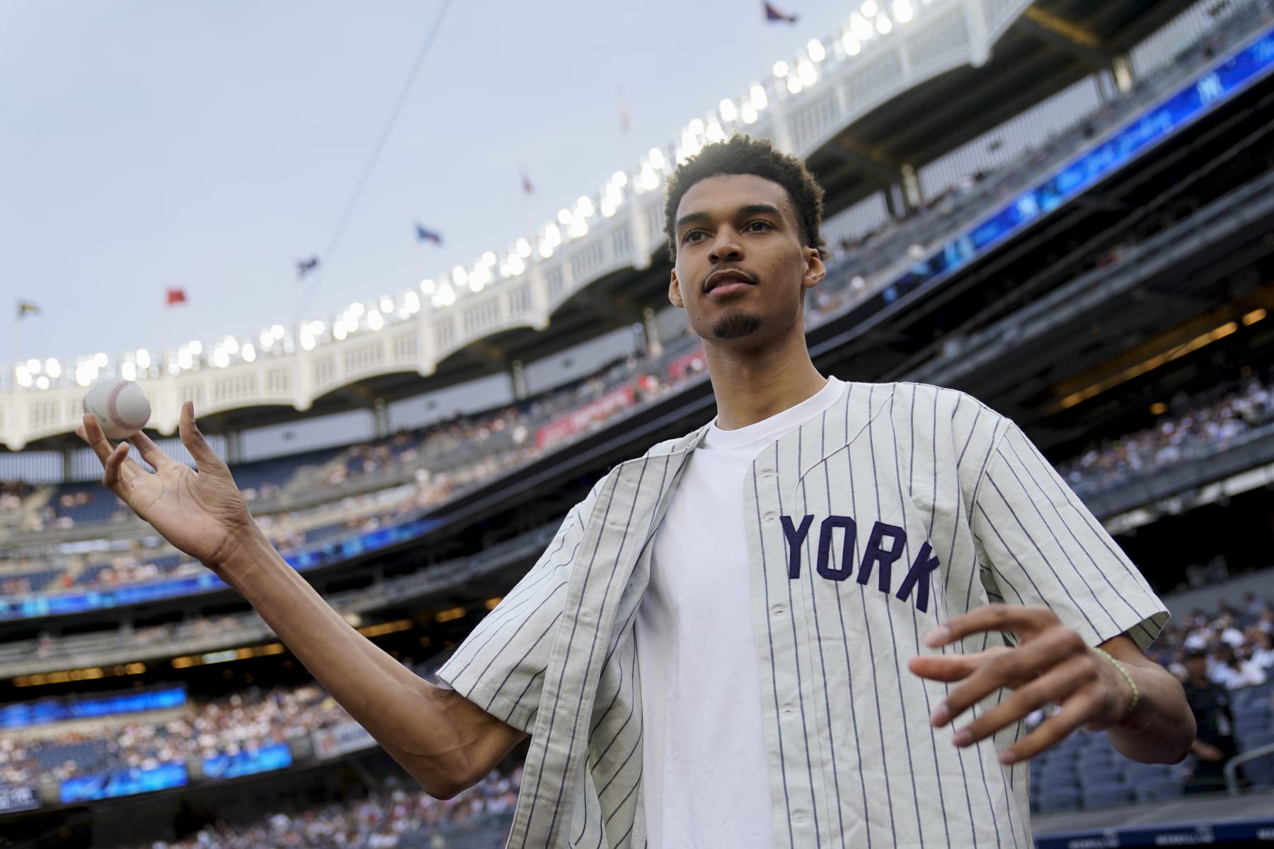 Victor Wembanyama, a projected first-round NBA draft pick, prepares to throw the ceremonial first pitch before a baseball game between the New York Yankees and the Seattle Mariners, Tuesday, June 20, 2023, in New York. (AP Photo/John Minchillo)