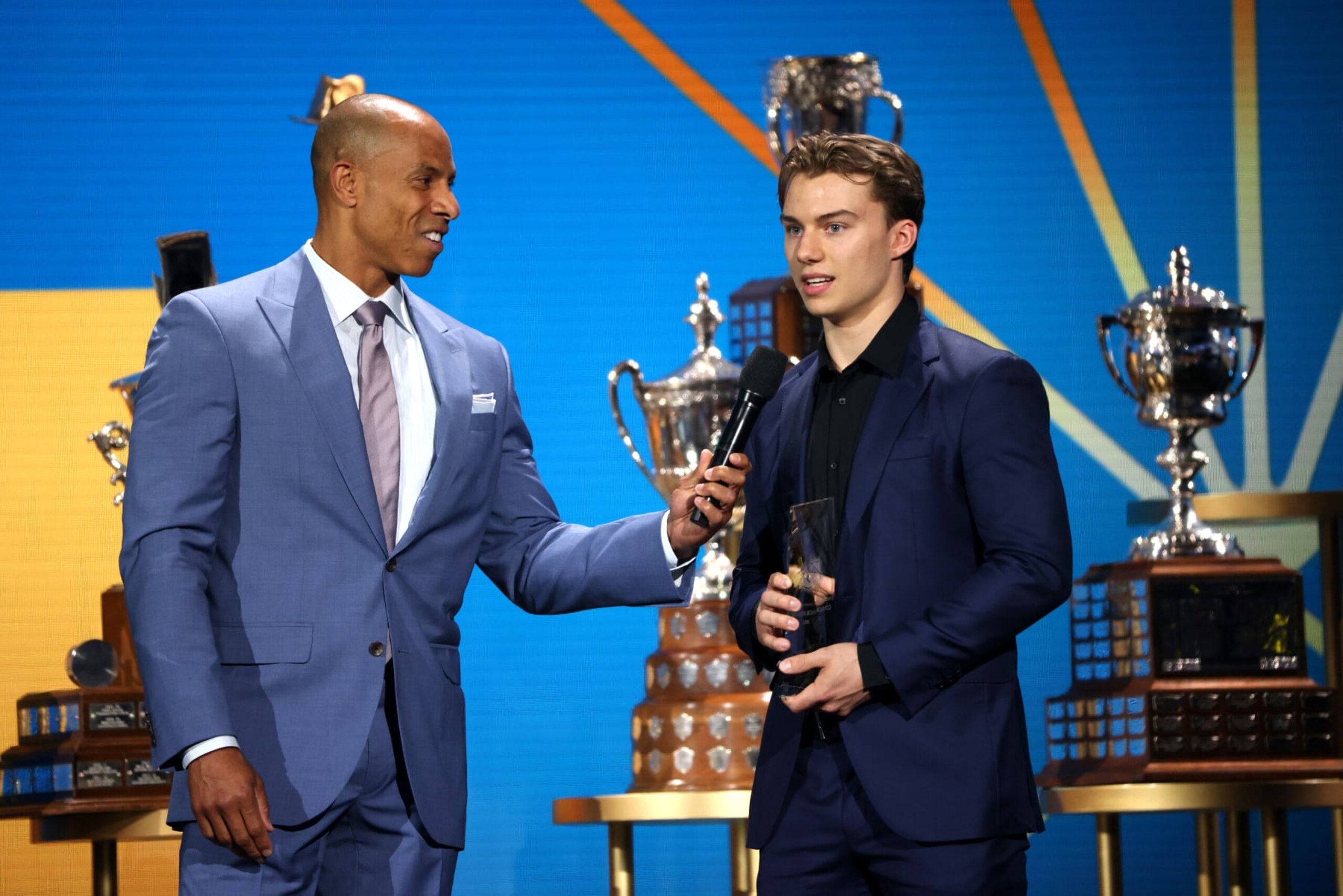 NASHVILLE, TENNESSEE - JUNE 26: Connor Bedard (R) speaks onstage with David Amber after Bedard was awarded the E.J. McGuire Award of Excellence at the 2023 NHL Awards at Bridgestone Arena on June 26, 2023 in Nashville, Tennessee. (Photo by Dave Sandford/NHLI via Getty Images)