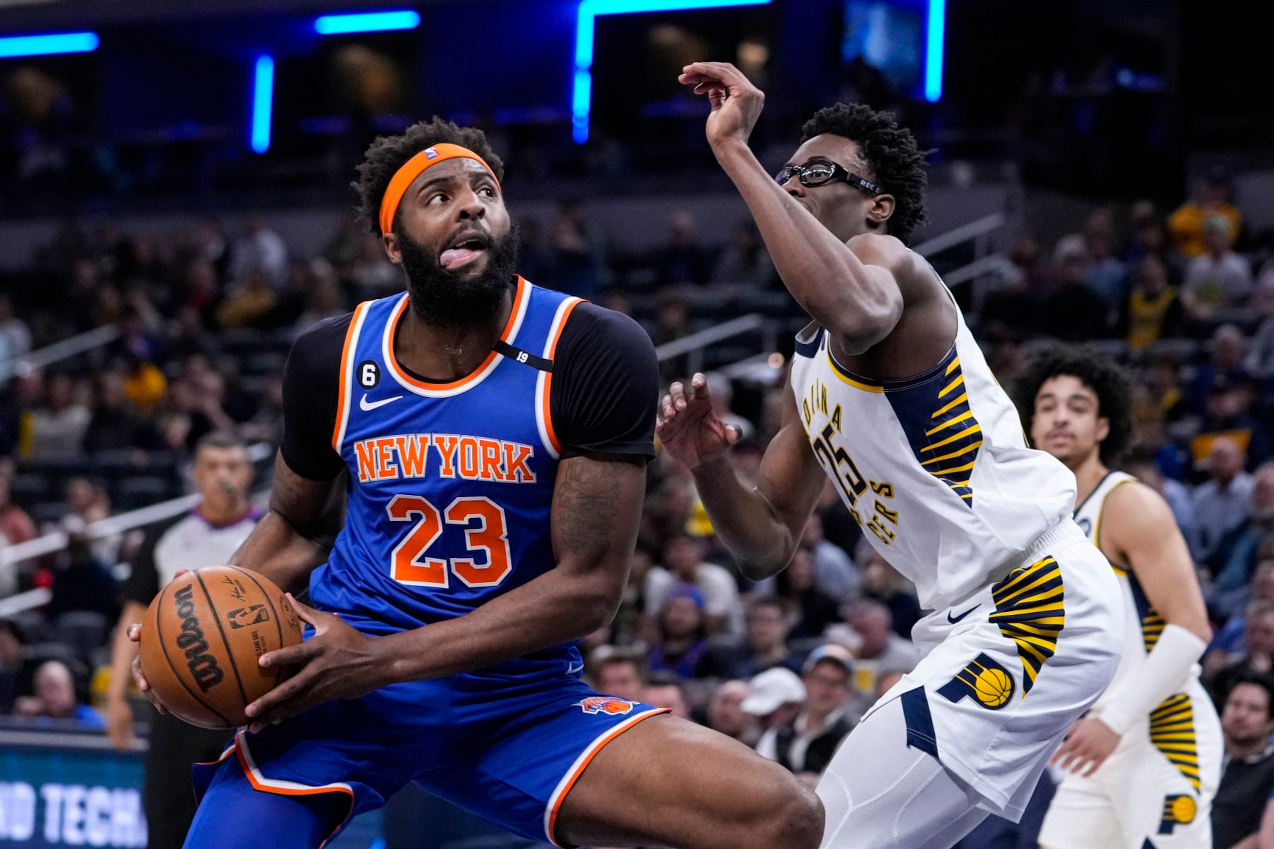 New York Knicks center Mitchell Robinson (23) drives on Indiana Pacers forward Serge Ibaka (25) during the first half of an NBA basketball game in Indianapolis, Wednesday, April 5, 2023. (AP Photo/Michael Conroy)