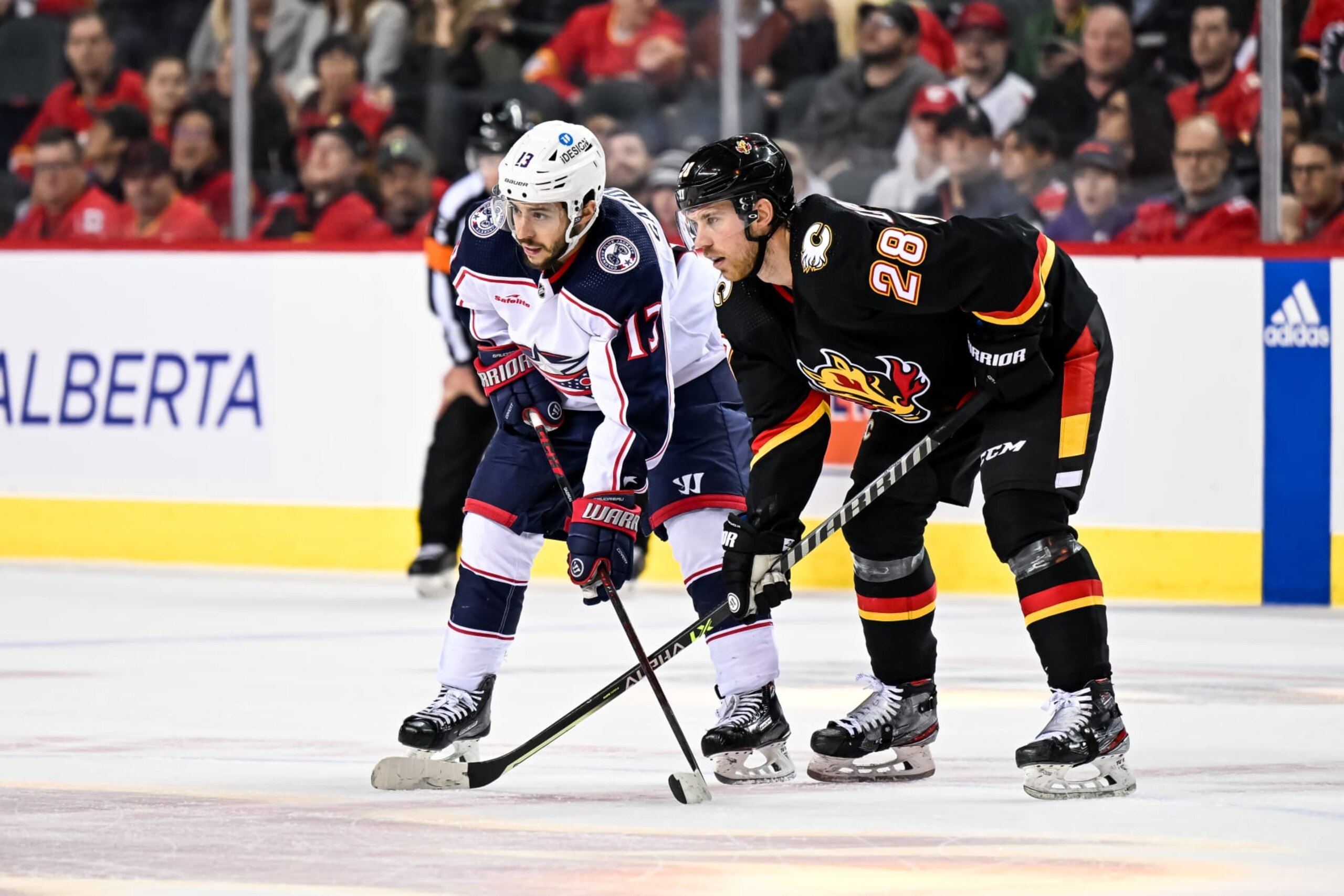 CALGARY, AB - JANUARY 23: Columbus Blue Jackets Left Wing Johnny Gaudreau (13) and Calgary Flames Center Elias Lindholm (28) get set for a face-off during the overtime period of an NHL game between the Calgary Flames and the Columbus Blue Jackets on January 23, 2023, at the Scotiabank Saddledome in Calgary, AB. (Photo by Brett Holmes/Icon Sportswire via Getty Images)