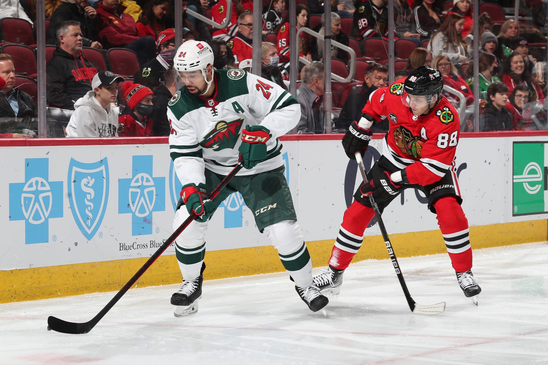 CHICAGO, ILLINOIS - JANUARY 21: Matt Dumba #24 of the Minnesota Wild grabs the puck ahead of Patrick Kane #88 of the Chicago Blackhawks in the second period at United Center on January 21, 2022 in Chicago, Illinois. (Photo by Chase Agnello-Dean/NHLI via Getty Images)
