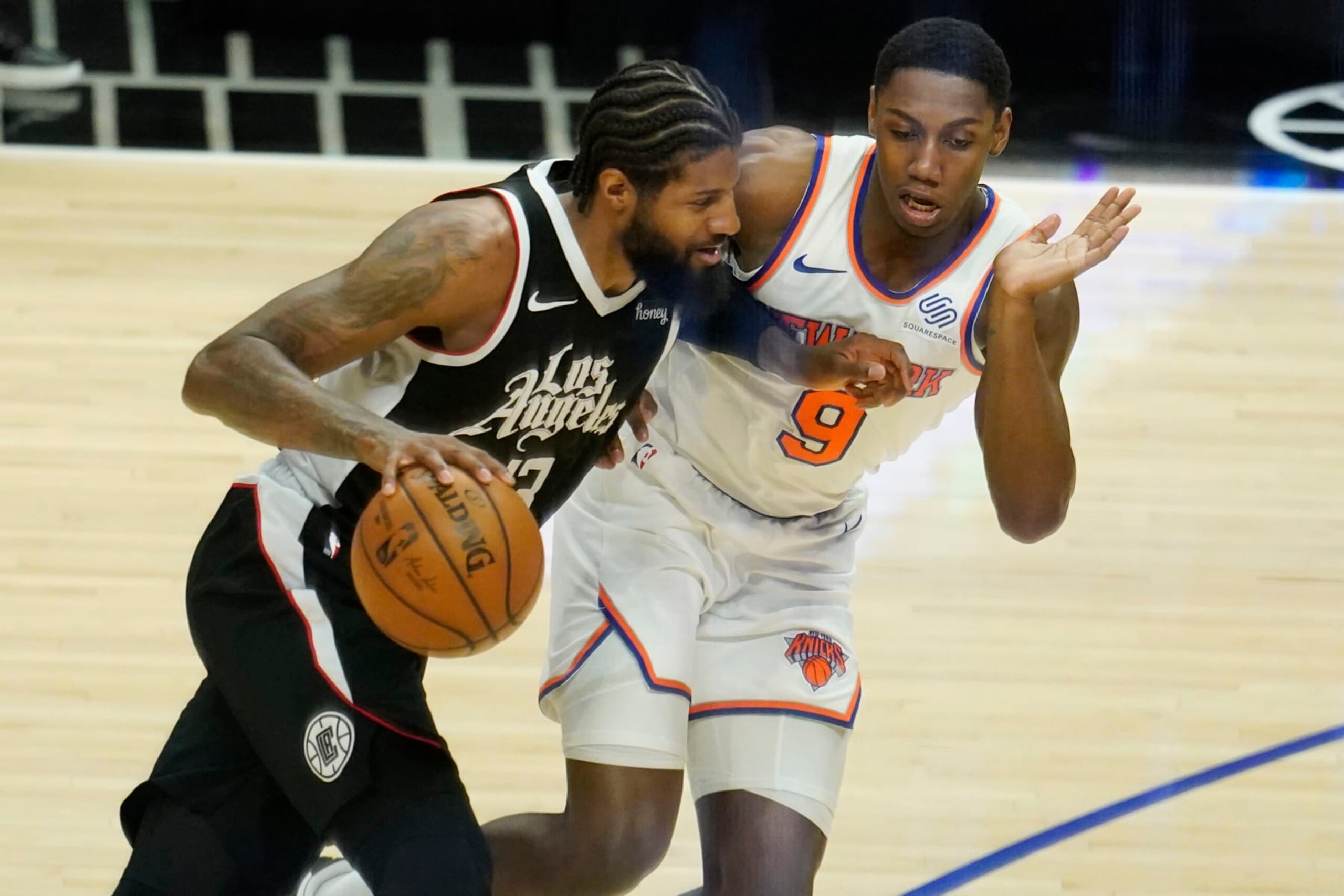 Los Angeles Clippers guard Paul George (13) is defended by New York Knicks guard RJ Barrett (9) during the second half of an NBA basketball game Sunday, May 9, 2021, in Los Angeles. (AP Photo/Marcio Jose Sanchez)