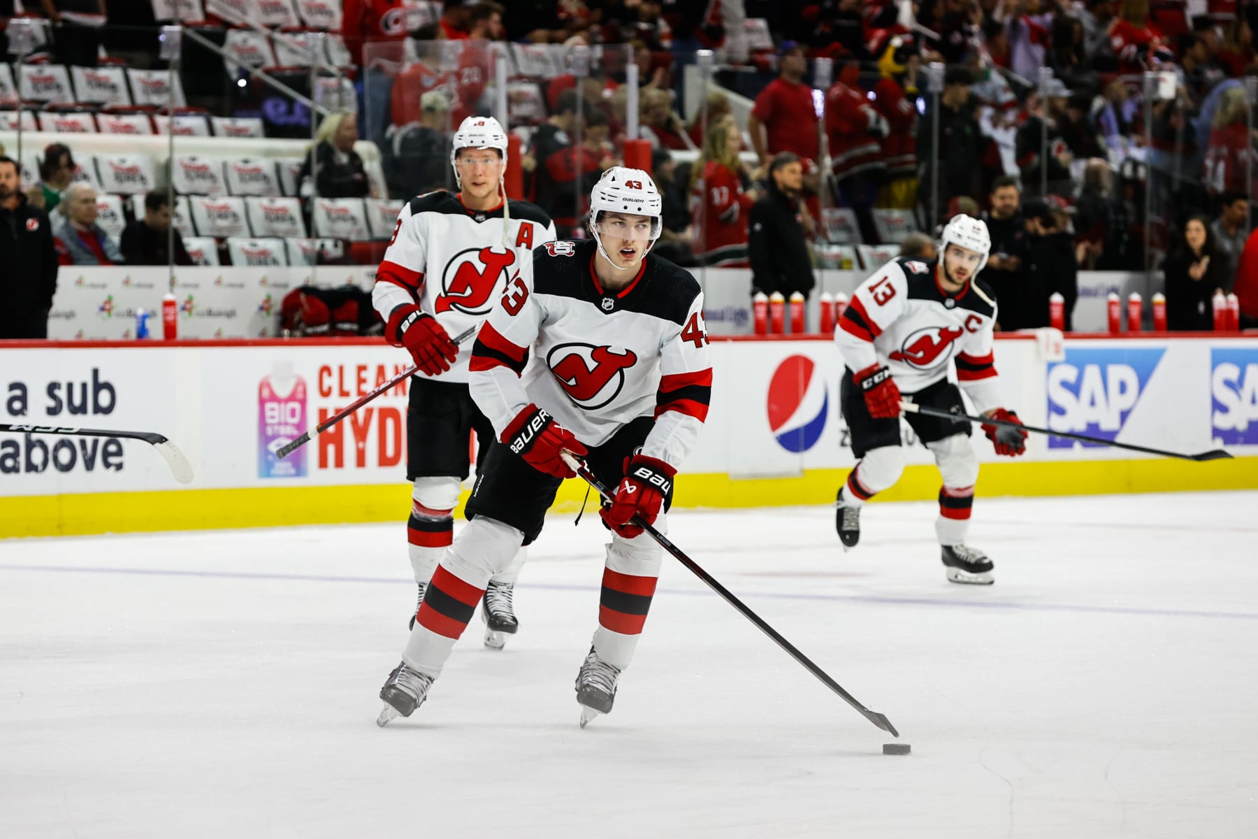 RALEIGH, NC - MAY 11: Luke Hughes #43 of the New Jersey Devils looks on with the puck against the Carolina Hurricanes during warmups prior to the start of Eastern Conference Game Five of the Second Round of the 2023 Stanley Cup Playoffs at PNC Arena on May 11, 2023 in Raleigh, North Carolina. (Photo by Jaylynn Nash/Getty Images)