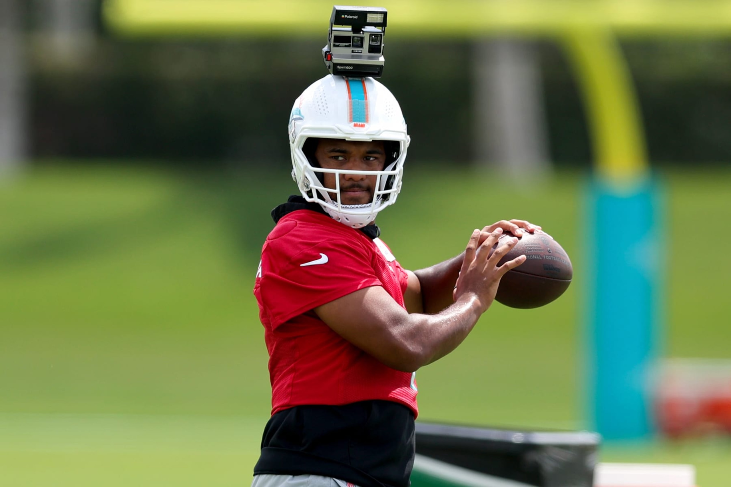 MIAMI GARDENS, FLORIDA - JUNE 08: Tua Tagovailoa #1 of the Miami Dolphins throws a pass with a Polaroid camera on his helmet during practice at Baptist Health Training Complex on June 08, 2023 in Miami Gardens, Florida. (Photo by Megan Briggs/Getty Images)