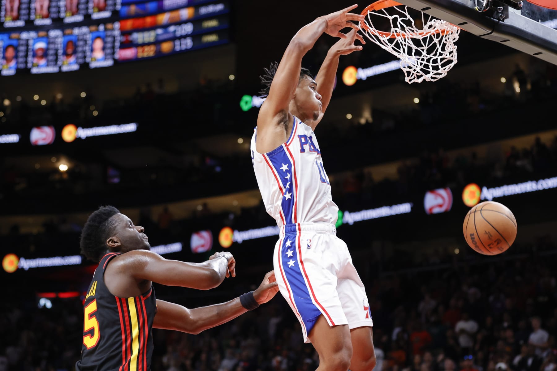 Philadelphia 76ers guard Jaden Springer, right, dunks next to Atlanta Hawks center Clint Capela during the second half of an NBA basketball game Friday, April 7, 2023, in Atlanta. (AP Photo/Alex Slitz)