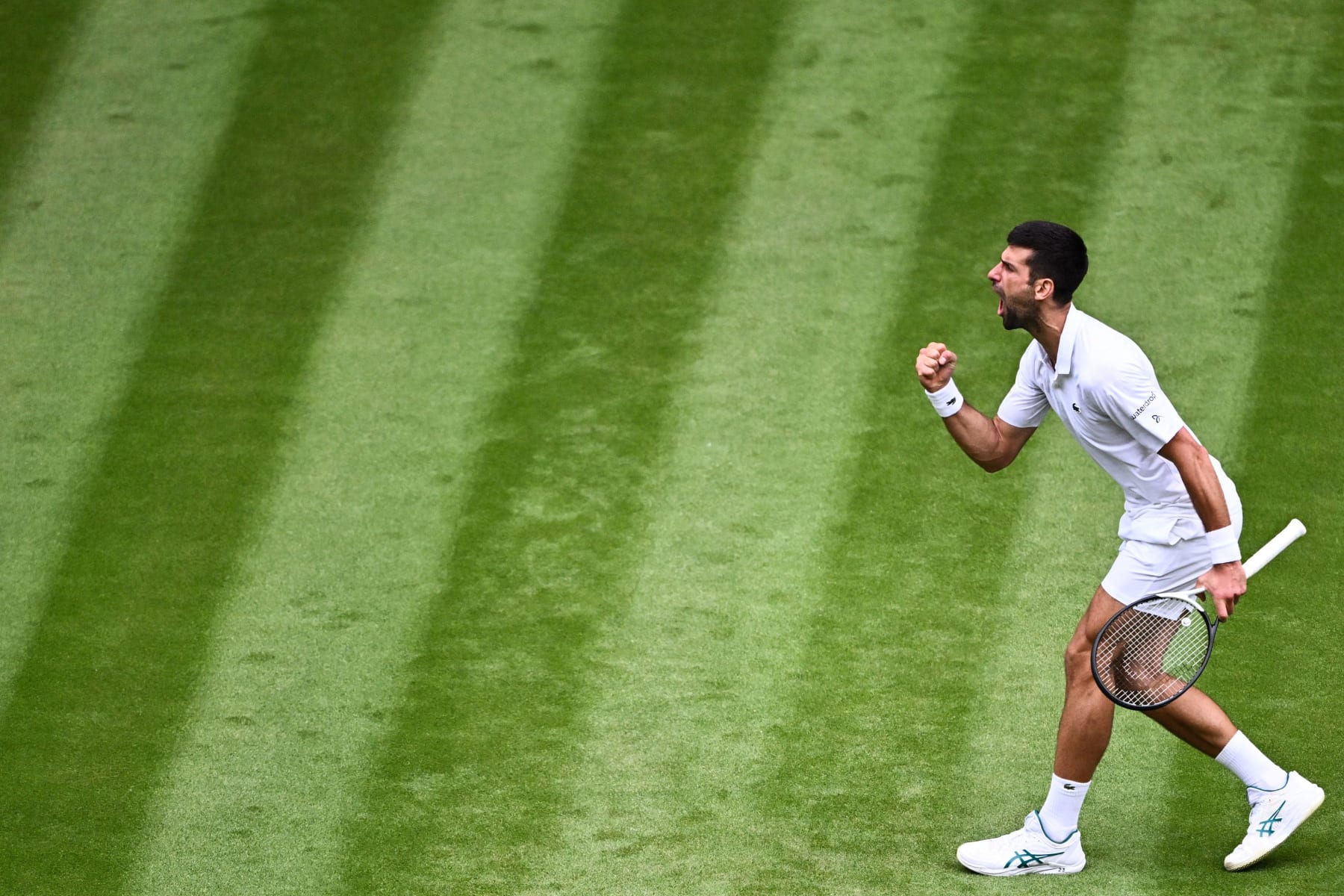 Serbia's Novak Djokovic celebrates winning the third set against Russia's Andrey Rublev during their men's singles quarter-finals tennis match on the ninth day of the 2023 Wimbledon Championships at The All England Tennis Club in Wimbledon, southwest London, on July 11, 2023. (Photo by SEBASTIEN BOZON / AFP) / RESTRICTED TO EDITORIAL USE (Photo by SEBASTIEN BOZON/AFP via Getty Images)