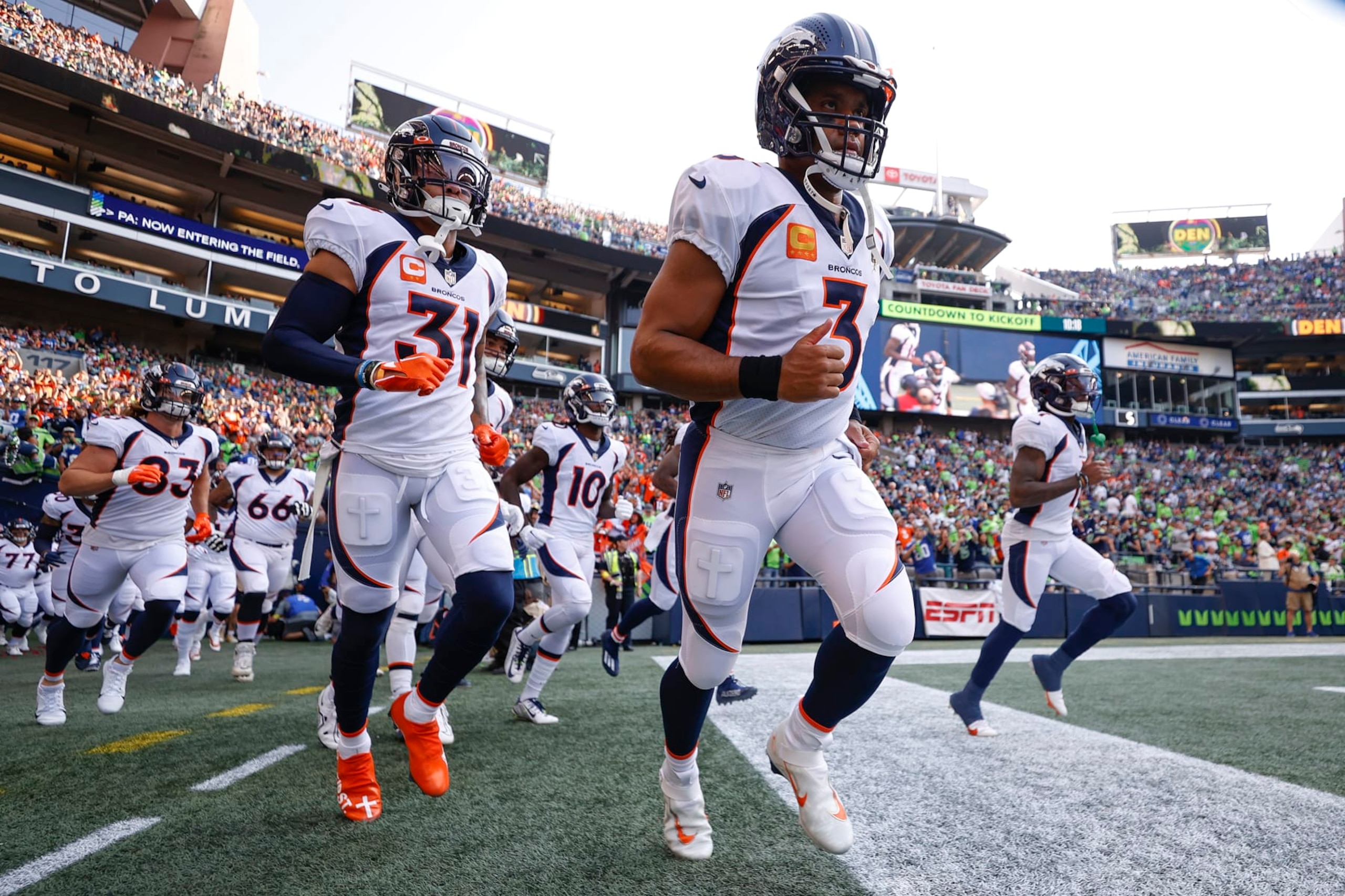 SEATTLE, WASHINGTON - SEPTEMBER 12: Justin Simmons #31 (L) and Russell Wilson #3 of the Denver Broncos (C) enter the field before playing against the Seattle Seahawks at Lumen Field on September 12, 2022 in Seattle, Washington. (Photo by Steph Chambers/Getty Images)