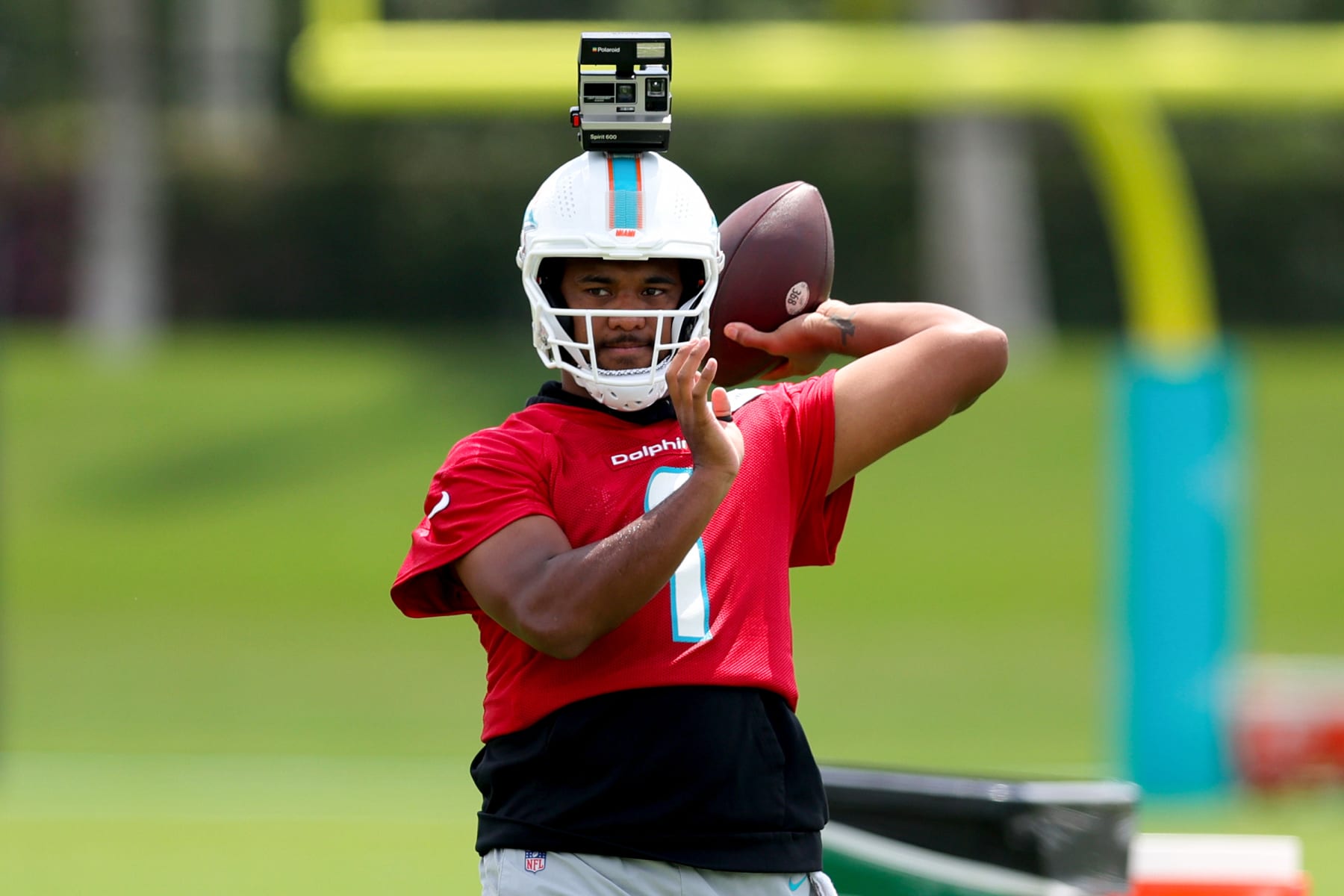 MIAMI GARDENS, FLORIDA - JUNE 08: Tua Tagovailoa #1 of the Miami Dolphins throws a pass with a Polaroid camera on his helmet during practice at Baptist Health Training Complex on June 08, 2023 in Miami Gardens, Florida. (Photo by Megan Briggs/Getty Images)