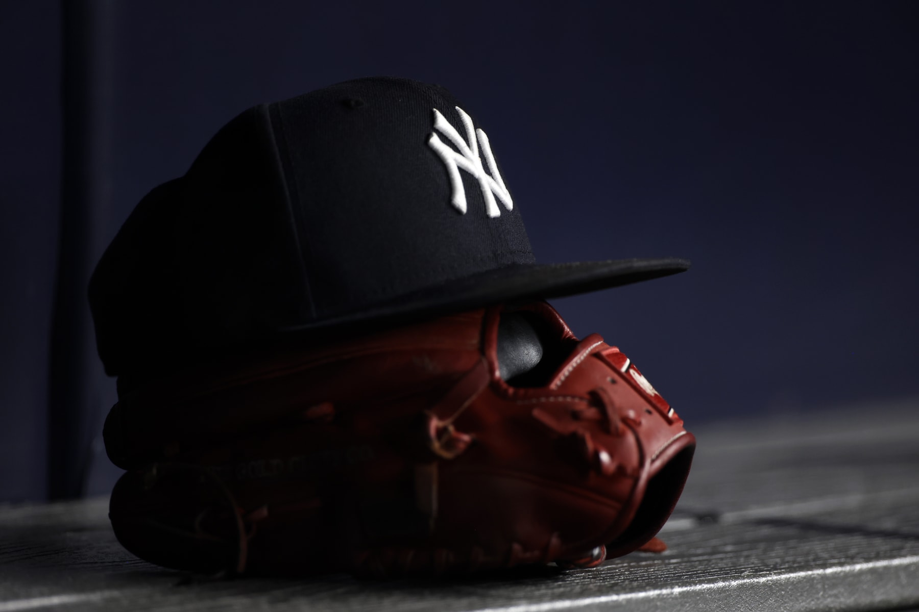 NEW YORK, NY - JUNE 6: A New York Yankees baseball hat sits on top of a glove in the Yankee dugout against the Boston Red Sox during the eighth inning at Yankee Stadium on June 6, 2021 in the Bronx borough of New York City. (Photo by Adam Hunger/Getty Images)