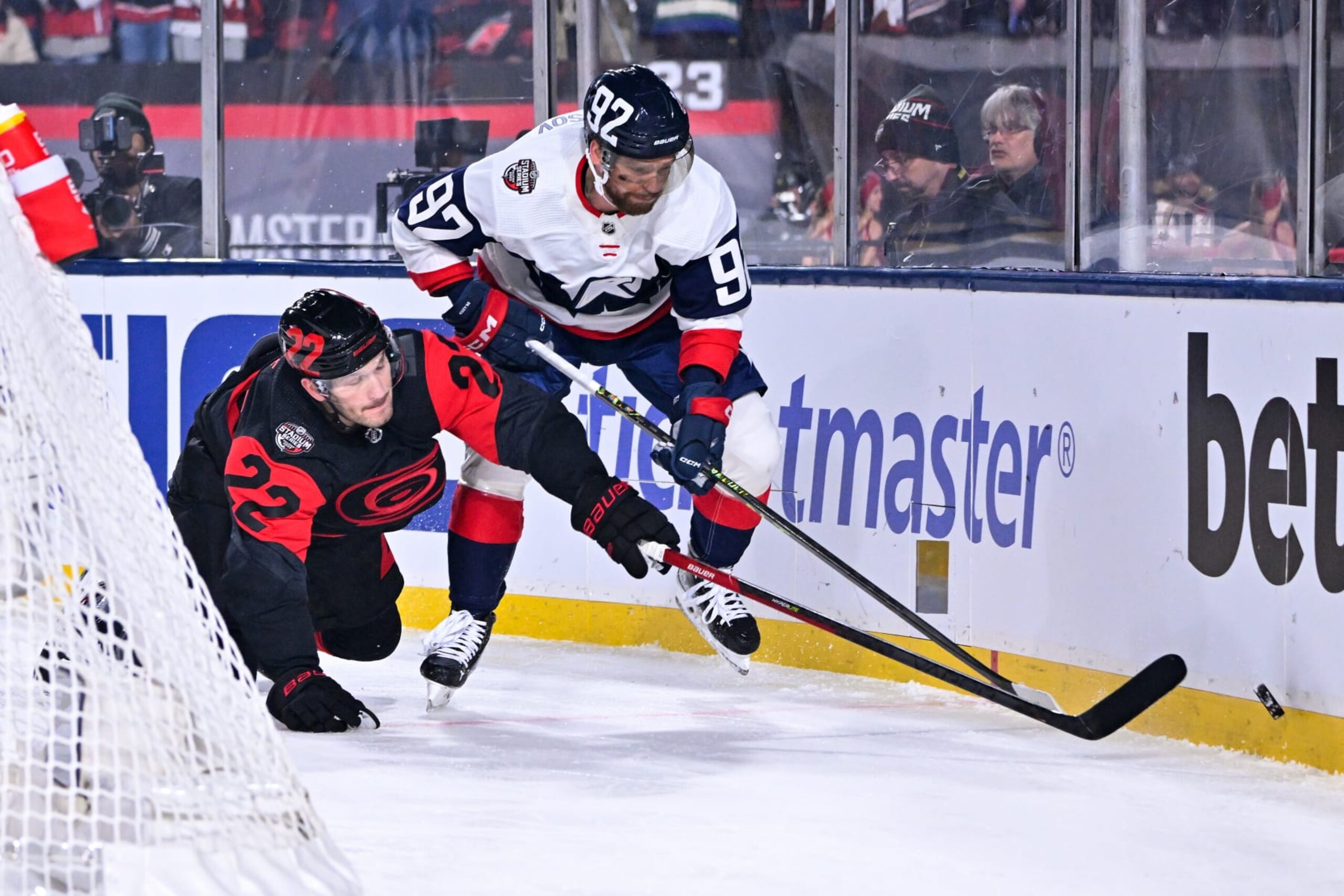RALEIGH, NORTH CAROLINA - FEBRUARY 18: Brett Pesce #22 of the Carolina Hurricanes and Evgeny Kuznetsov #92 of the Washington Capitals compete for the puck during the second period in the 2023 Navy Federal Credit Union NHL Stadium Series at Carter-Finley Stadium on February 18, 2023 in Raleigh, North Carolina. (Photo by Grant Halverson/Getty Images)