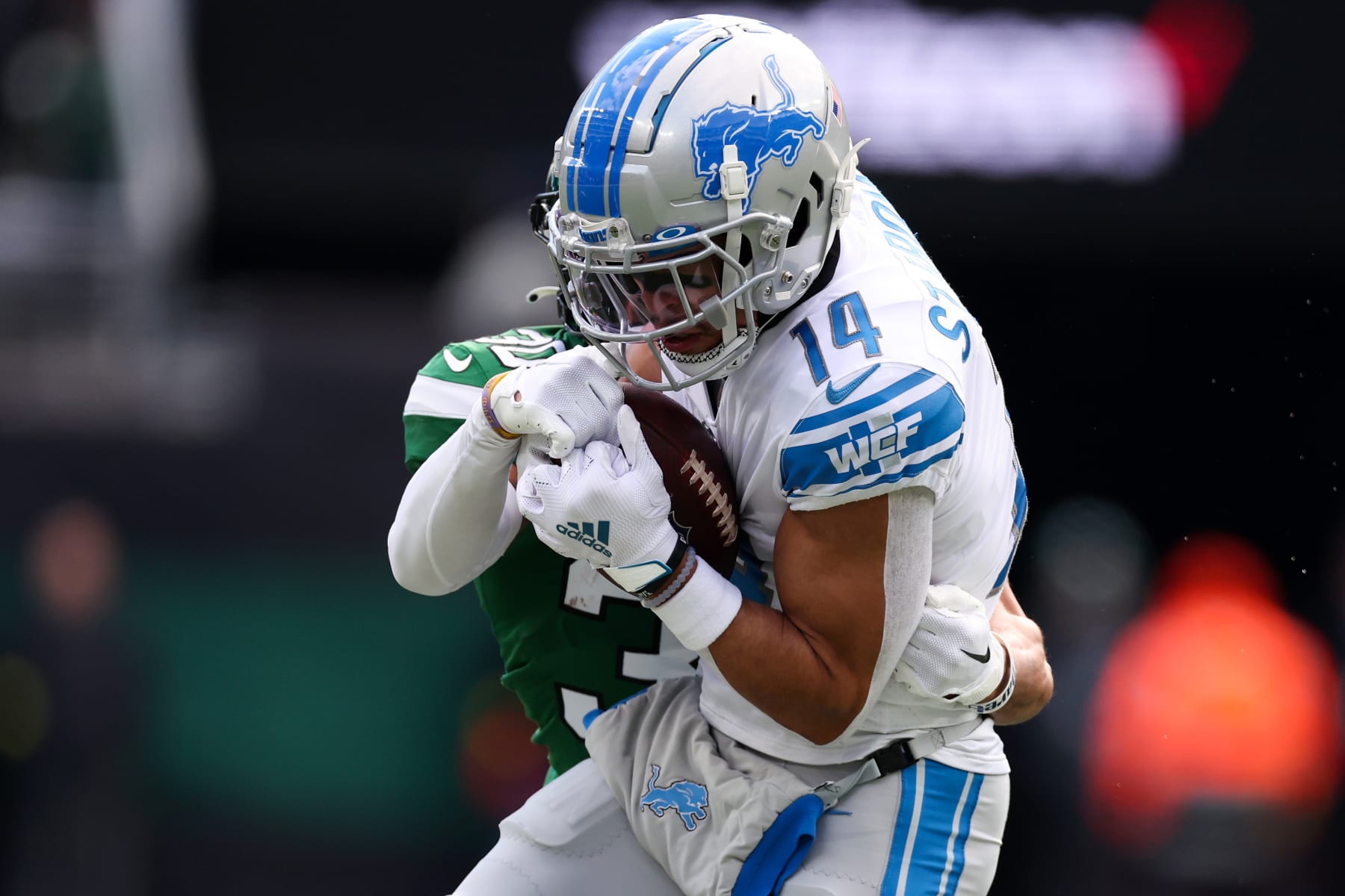 EAST RUTHERFORD, NEW JERSEY - DECEMBER 18: Amon-Ra St. Brown #14 of the Detroit Lions catches the ball as Michael Carter II #30 of the New York Jets defends during the first quarter at MetLife Stadium on December 18, 2022 in East Rutherford, New Jersey. (Photo by Al Bello/Getty Images)