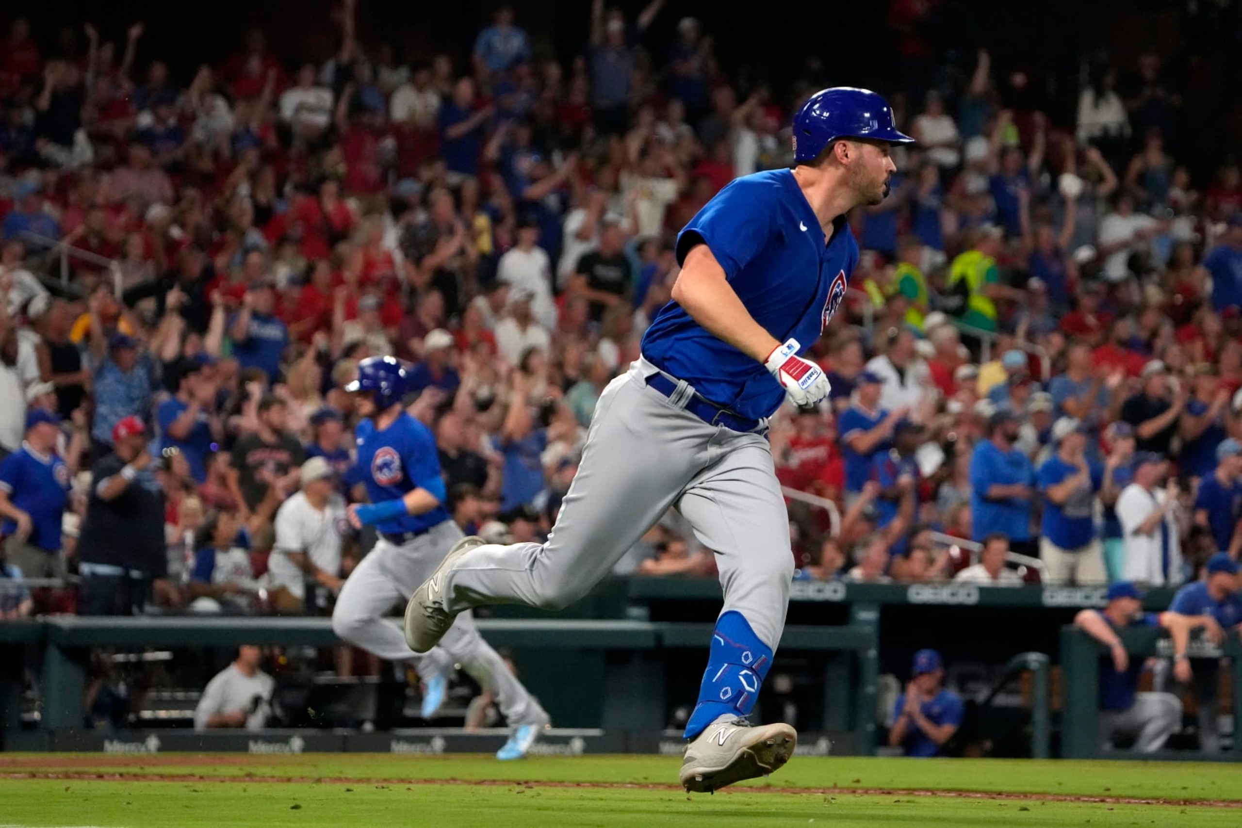 Chicago Cubs' Trey Mancini heads to first on an RBI single as Ian Happ, left, comes in to score during the sixth inning of a baseball game Friday, July 28, 2023, in St. Louis. (AP Photo/Jeff Roberson)