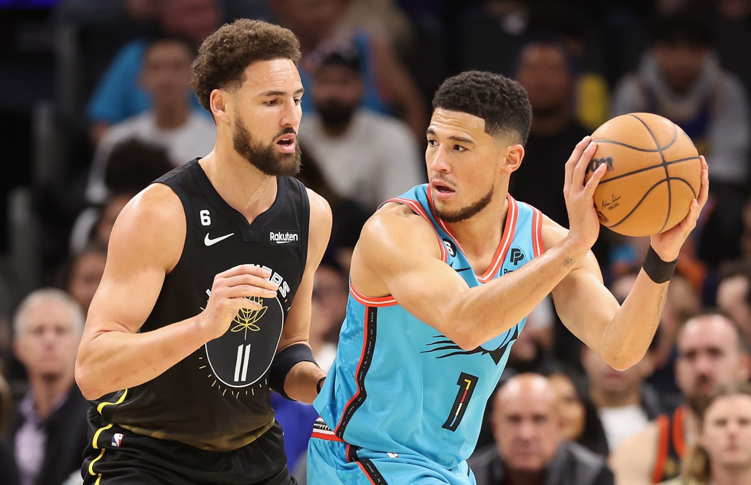 PHOENIX, ARIZONA - NOVEMBER 16: Devin Booker #1 of the Phoenix Suns handles the ball against Klay Thompson #11 of the Golden State Warriors during the first half of the NBA game at Footprint Center on November 16, 2022 in Phoenix, Arizona. NOTE TO USER: User expressly acknowledges and agrees that, by downloading and or using this photograph, User is consenting to the terms and conditions of the Getty Images License Agreement.  (Photo by Christian Petersen/Getty Images)