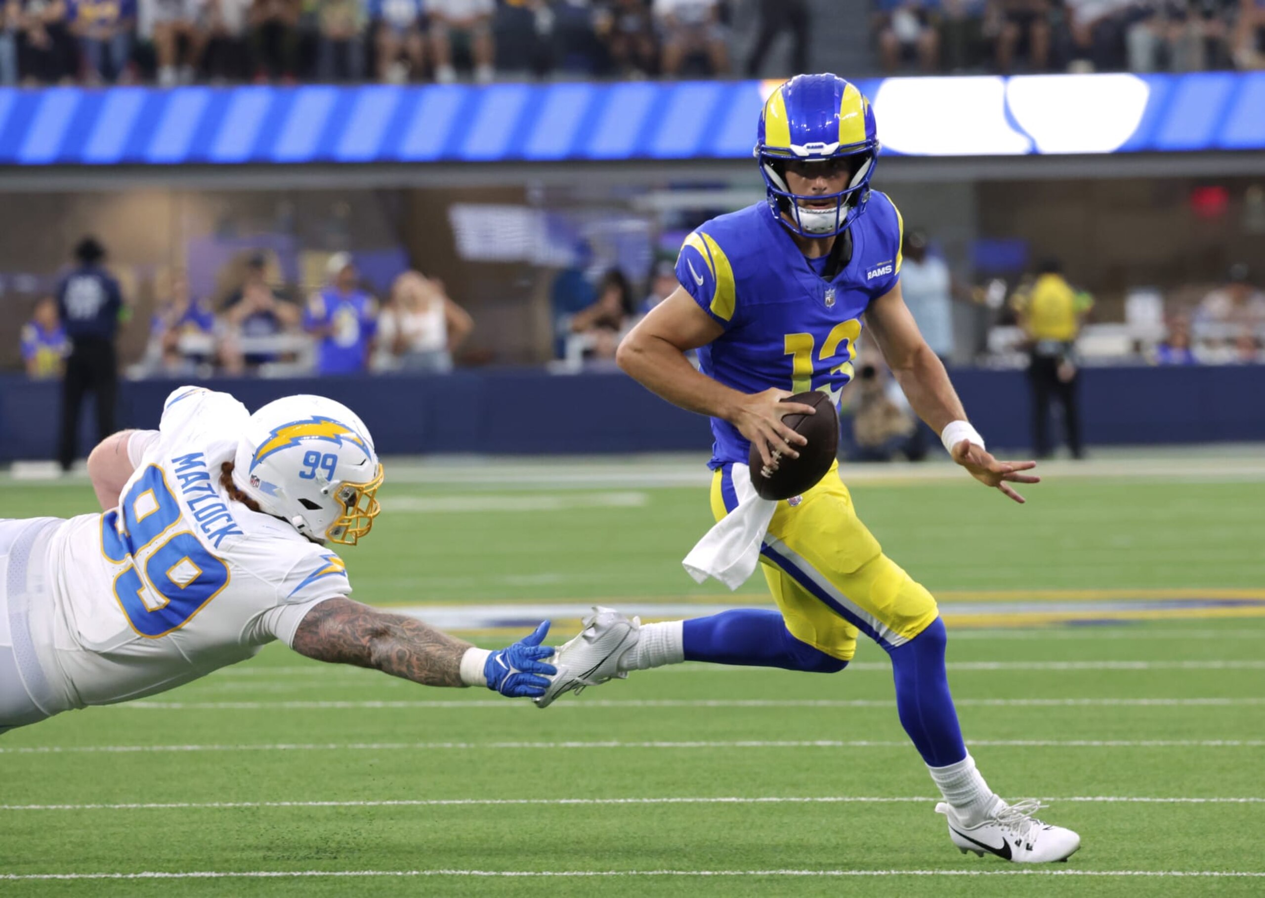 INGLEWOOD, CA - AUGUST 12: Rams quarterback Stetson Bennett scrambles away fron Chargers Scott Matlock in the second quarter during the Rams and Chargers preseason game at SoFi Stadium in Inglewood, CA on Saturday, Aug. 12, 2023. (Myung J. Chun / Los Angeles Times via Getty Images)