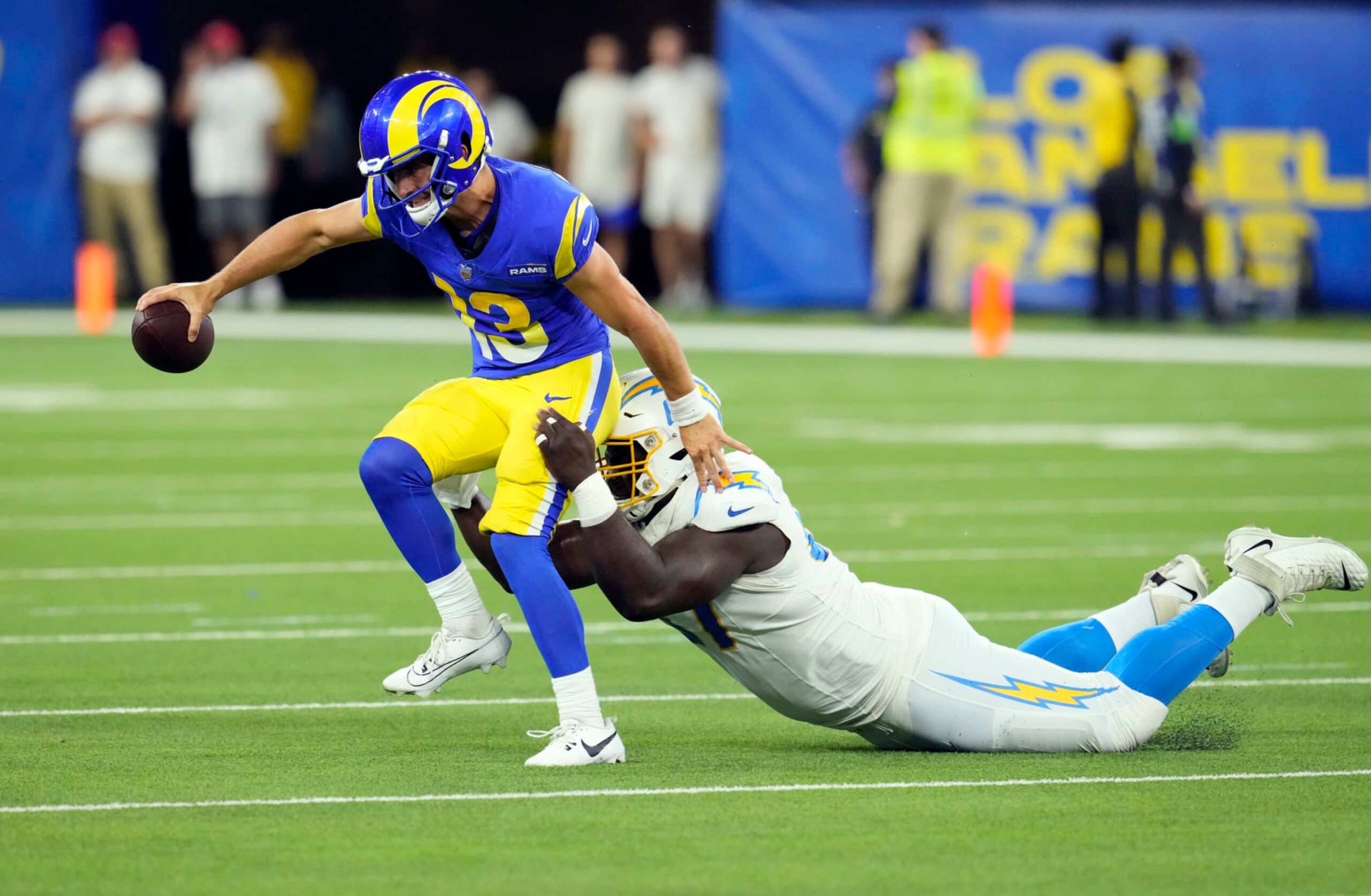 INGLEWOOD, CALIFORNIA - AUGUST 12: Quarterback Stetson Bennett #13 of the Los Angeles Rams is sacked by defensive tackle CJ Okoye #67 of the Los Angeles Chargers during the second half of a pre-season NFL game at SoFi Stadium on August 12, 2023 in Inglewood, California. (Photo by Kevork Djansezian/Getty Images)