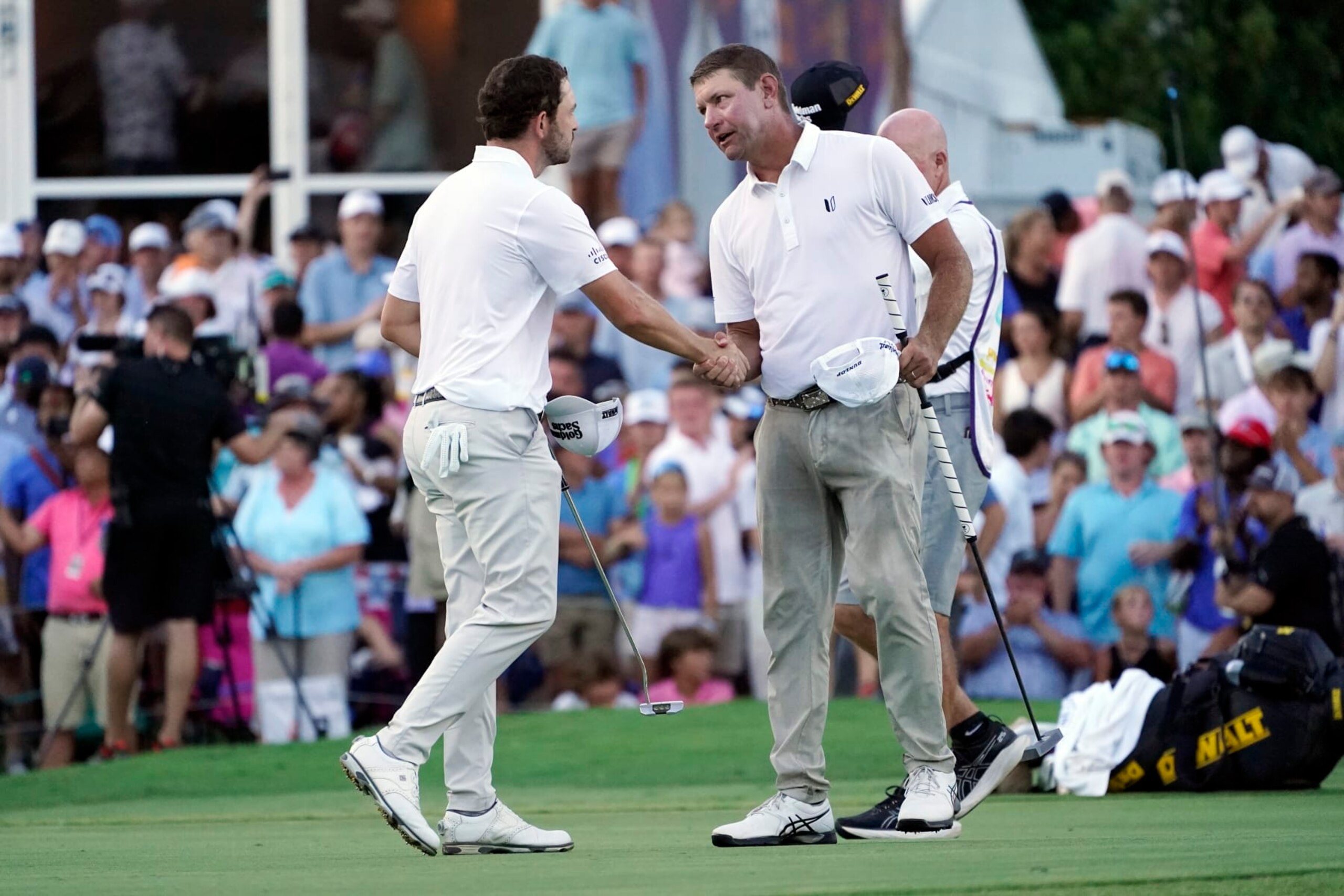 Lucas Glover, right, shakes hands with Patrick Cantlay on the 18th green after Glover won the St. Jude Championship golf tournament in a playoff Sunday, Aug. 13, 2023, in Memphis, Tenn. (AP Photo/George Walker IV)