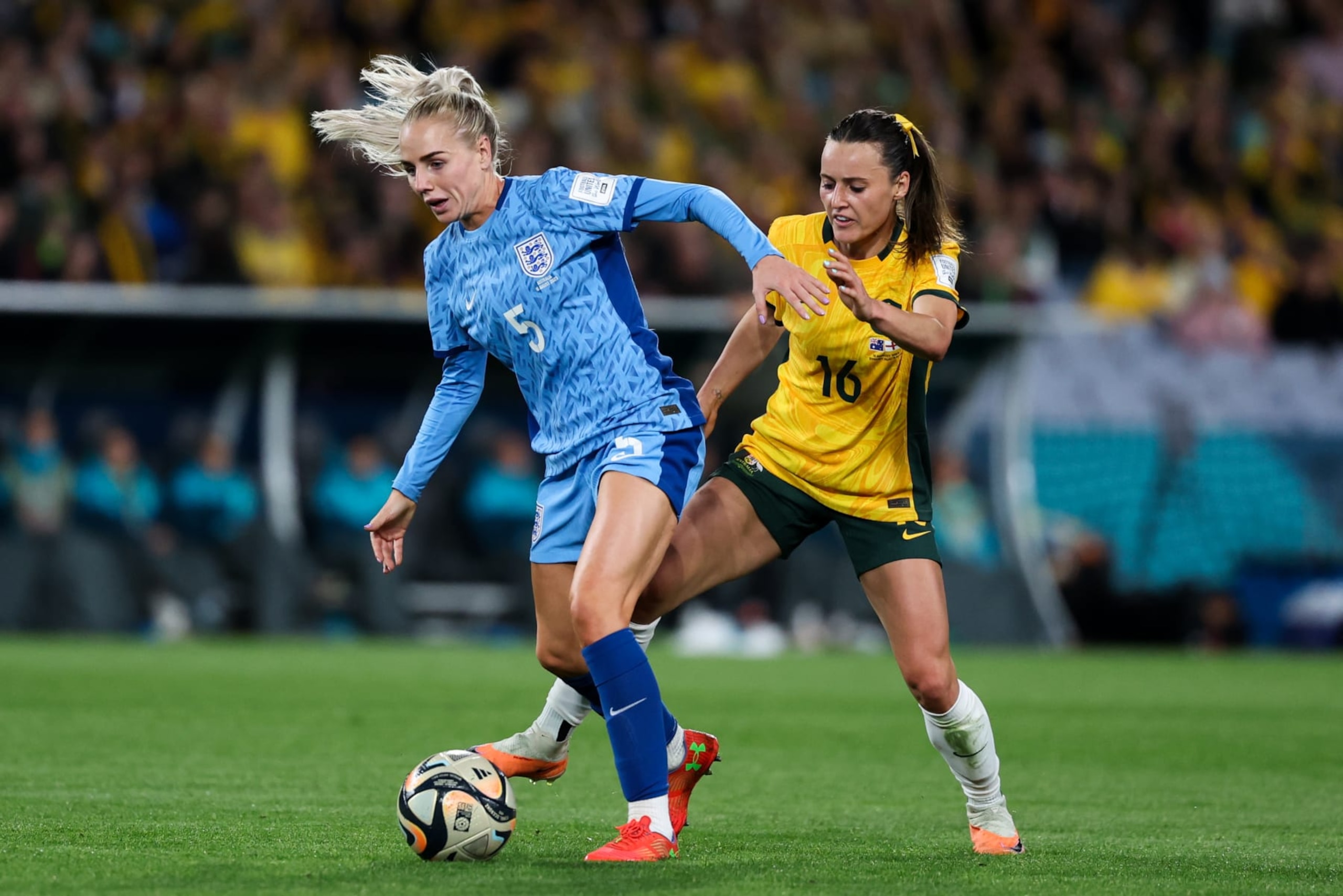 SYDNEY, AUSTRALIA - AUGUST 16: Hayley Raso #16 of Australia competes for the ball with Alex Greenwood #5 of England during the FIFA Women's World Cup Australia & New Zealand 2023 Semi Final match between Australia and England at Stadium Australia on August 16, 2023 in Sydney, Australia. (Photo by Zhizhao Wu/Getty Images)
