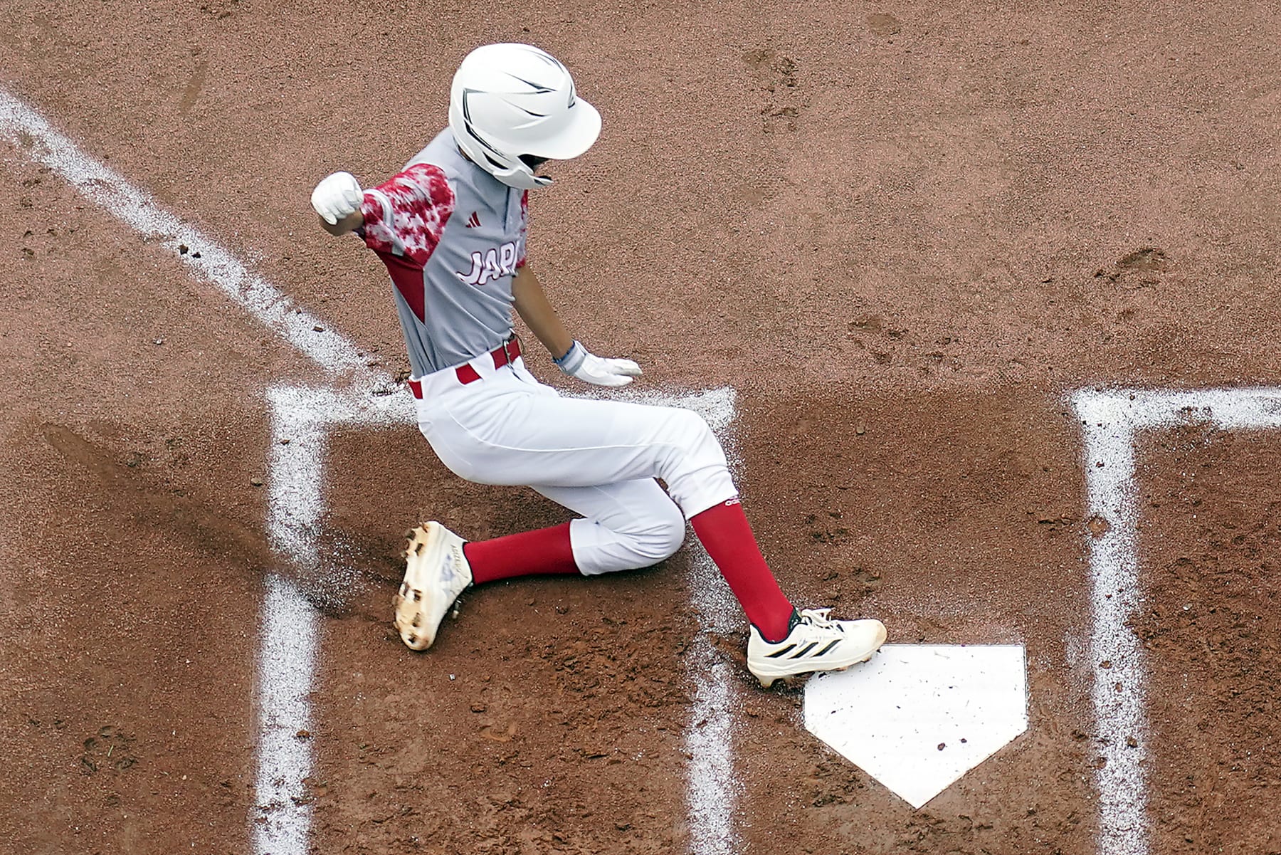 Japan's Hinata Uchigaki (14) slides into home scoring on a double by Yohei Yamaguchi against Cuba during the first inning of a baseball game at the Little League World Series tournament in South Williamsport, Pa., Wednesday, Aug. 16, 2023. Japan won the game 1-0. (AP Photo/Tom E. Puskar)