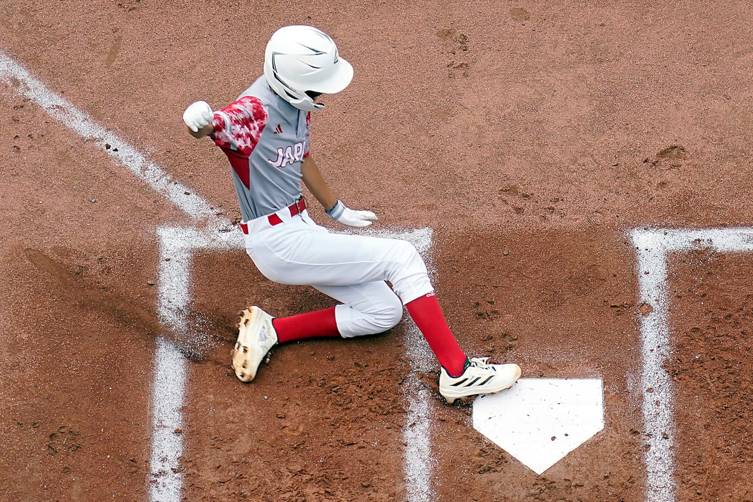 Japan's Hinata Uchigaki (14) slides into home scoring on a double by Yohei Yamaguchi against Cuba during the first inning of a baseball game at the Little League World Series tournament in South Williamsport, Pa., Wednesday, Aug. 16, 2023. Japan won the game 1-0. (AP Photo/Tom E. Puskar)