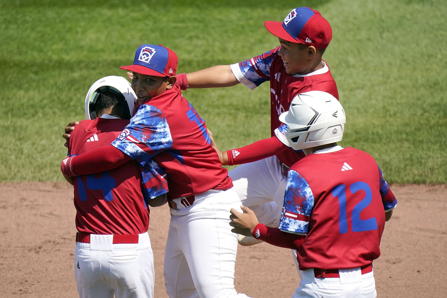 Cuba's Luis Gurriel (14) is mobbed by teammates Didier Castillo (15), Edgar Torrez and Liusban Sanchez (12) after he drove in the final run of their 11-1 win against Australia during a baseball game at the Little League World Series tournament in South Williamsport, Pa., Saturday, Aug. 19, 2023. (AP Photo/Tom E. Puskar)
