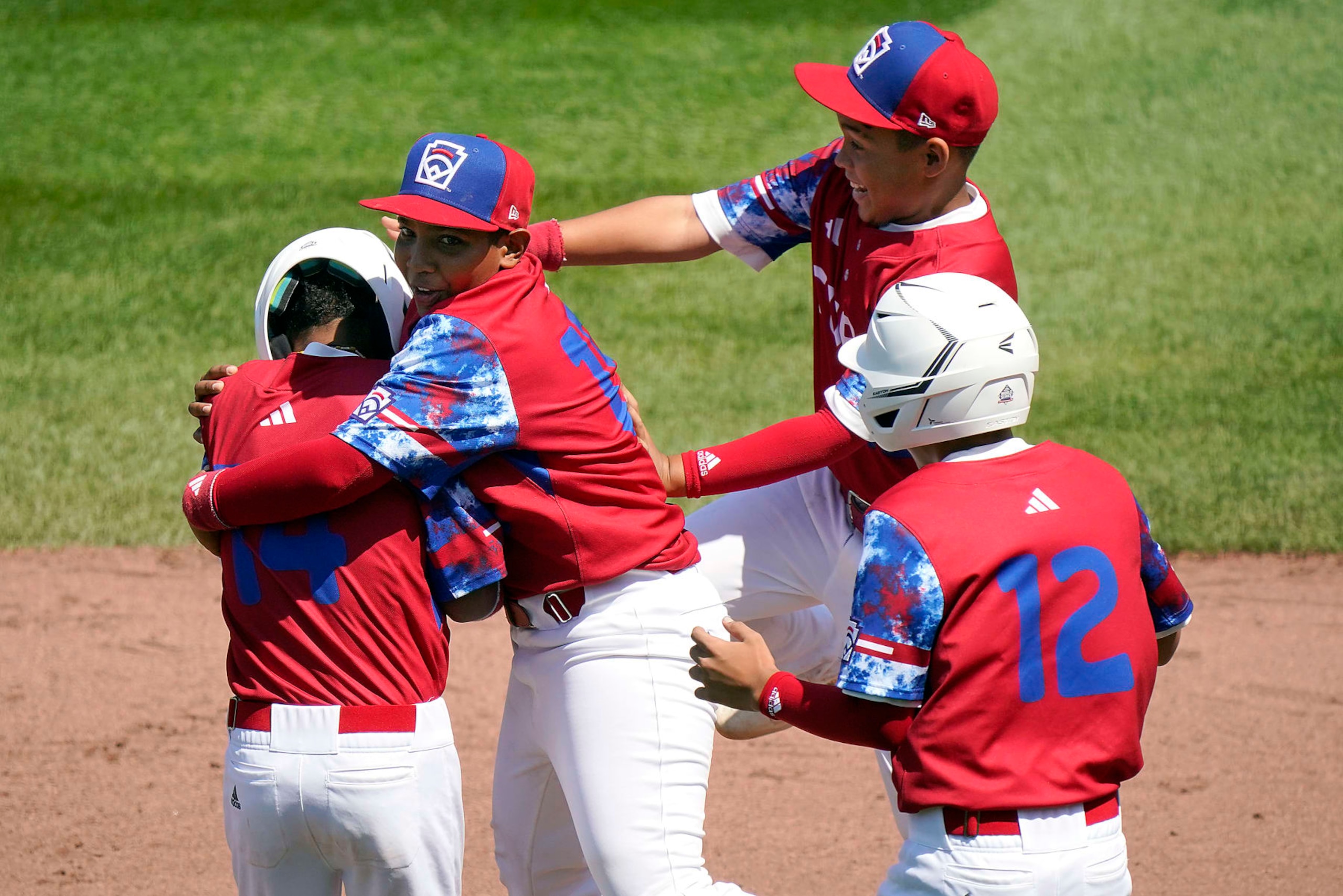 Cuba's Luis Gurriel (14) is mobbed by teammates Didier Castillo (15), Edgar Torrez and Liusban Sanchez (12) after he drove in the final run of their 11-1 win against Australia during a baseball game at the Little League World Series tournament in South Williamsport, Pa., Saturday, Aug. 19, 2023. (AP Photo/Tom E. Puskar)
