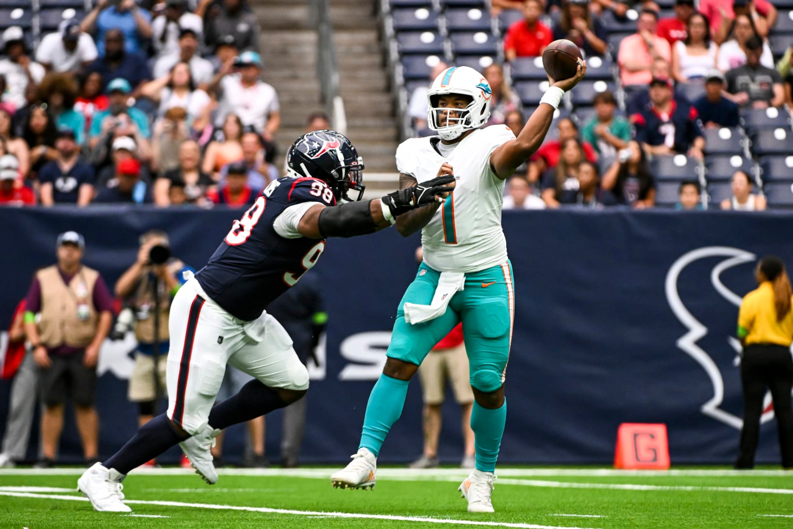 HOUSTON, TEXAS - AUGUST 19: Tua Tagovailoa #1 of the Miami Dolphins passes the ball under pressure by Sheldon Rankins #98 of the Houston Texans during the preseason game at NRG Stadium on August 19, 2023 in Houston, Texas. (Photo by Logan Riely/Getty Images)