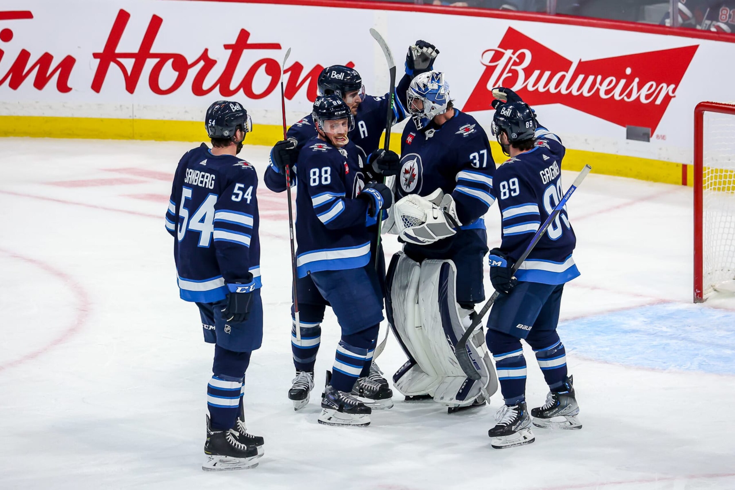 WINNIPEG, CANADA - DECEMBER 6: Dylan Samberg #54, Nate Schmidt #88, Mark Scheifele #55, goaltender Connor Hellebuyck #37 and Sam Gagner #89 of the Winnipeg Jets celebrate a 5-2 victory over the Florida Panthers at the Canada Life Centre on December 6, 2022 in Winnipeg, Manitoba, Canada. (Photo by Jonathan Kozub/NHLI via Getty Images)