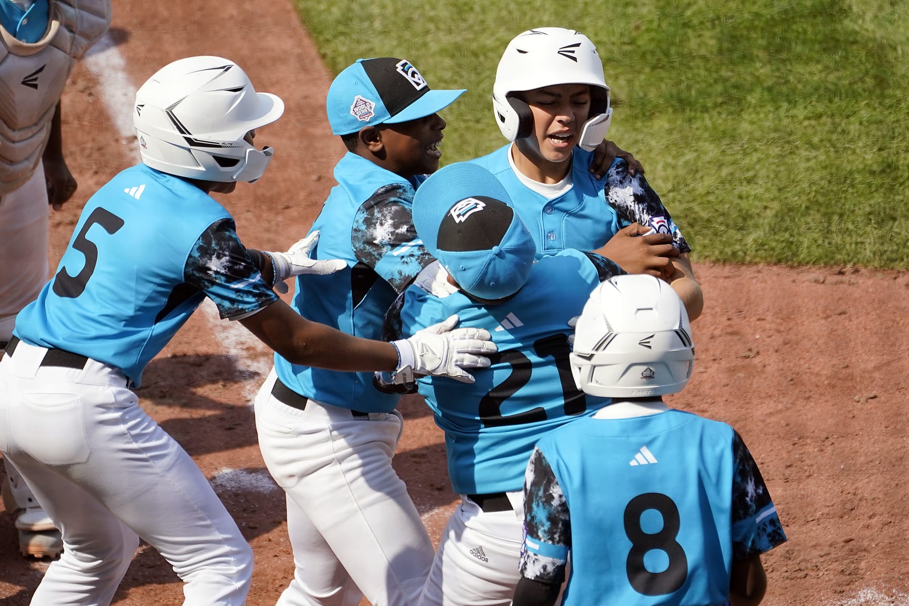 Curacao's Nasir El-Ossais, center, is greeted at home plate after his two run home run off of Venezuela's Osman Basabe during the sixth inning of a baseball game at the Little League World Series tournament in South Williamsport, Pa., Monday, Aug. 21, 2023. Curacao won the game 2-1. (AP Photo/Tom E. Puskar) Curacao's Nasir El-Ossais, center, is greeted at home plate after his two run home run off of Venezuela's Osman Basabe during the sixth inning of a baseball game at the Little League World Series tournament in South Williamsport, Pa., Monday, Aug. 21, 2023. Curacao won the game 2-1. (AP Photo/Tom E. Puskar)