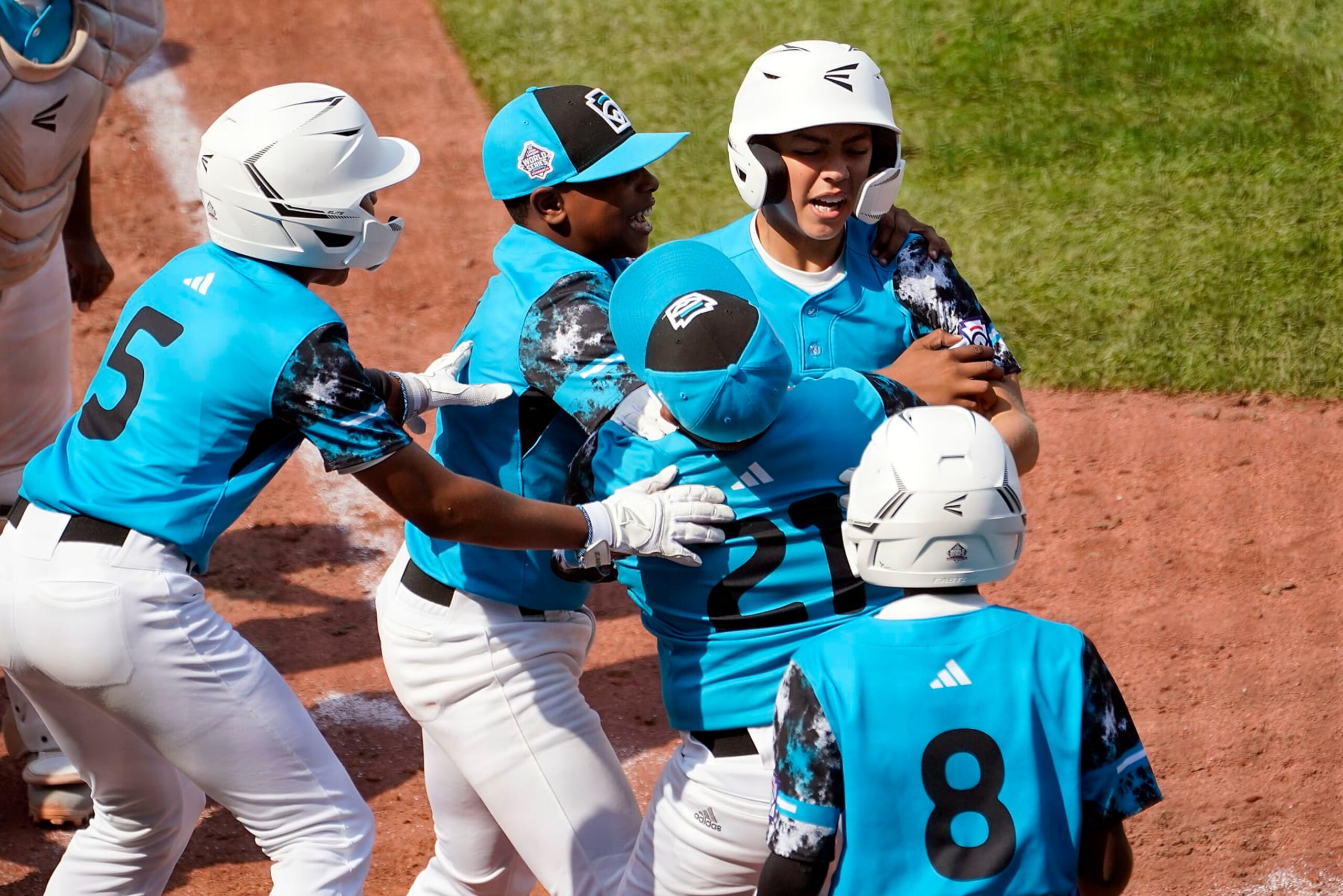 Curacao's Nasir El-Ossais, center, is greeted at home plate after his two run home run off of Venezuela's Osman Basabe during the sixth inning of a baseball game at the Little League World Series tournament in South Williamsport, Pa., Monday, Aug. 21, 2023. Curacao won the game 2-1. (AP Photo/Tom E. Puskar)