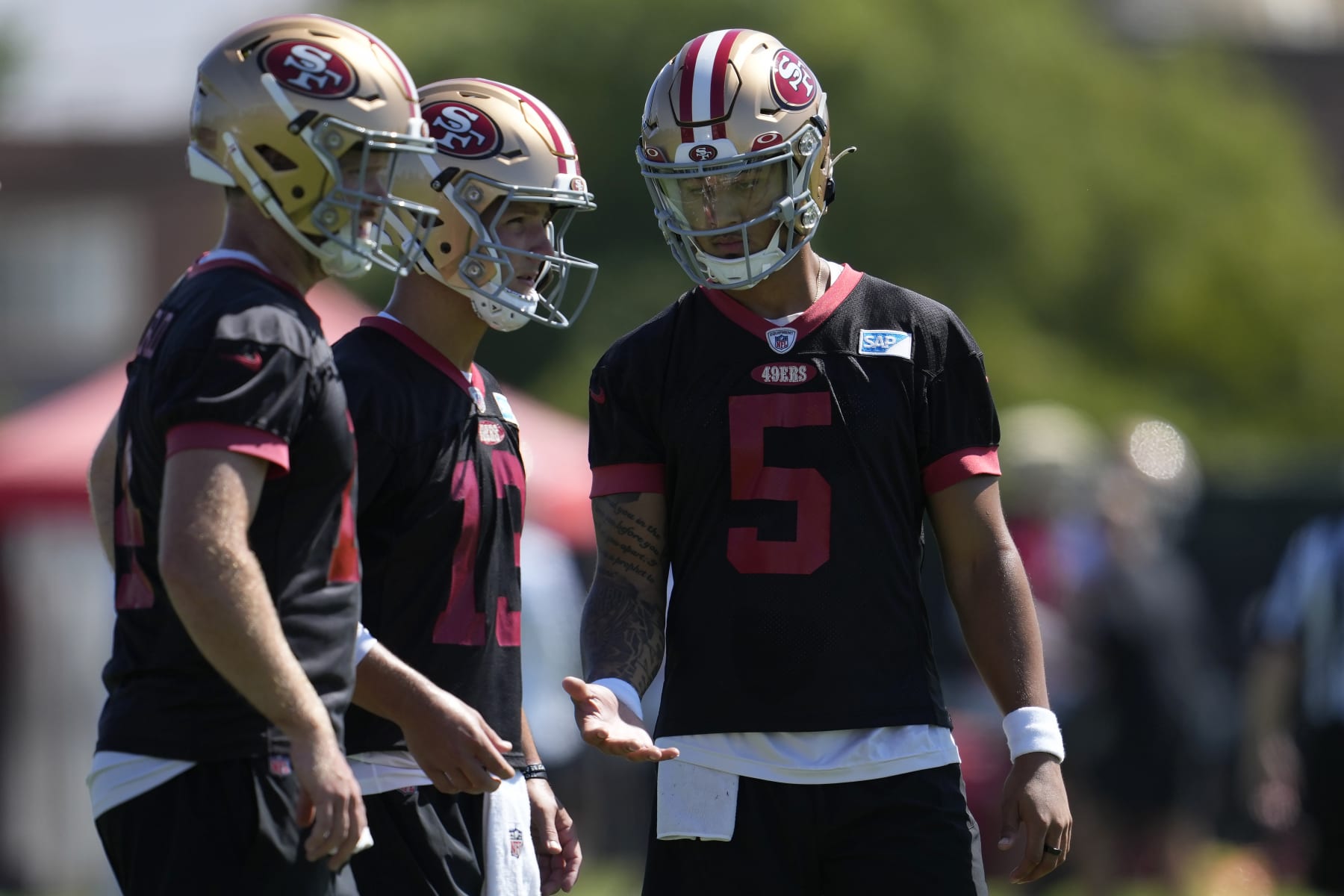 San Francisco 49ers quarterbacks Sam Darnold, left, Brock Purdy, middle, and Trey Lance (5) stand on the field during the NFL team's football training camp in Santa Clara, Calif., Thursday, July 27, 2023. (AP Photo/Jeff Chiu)