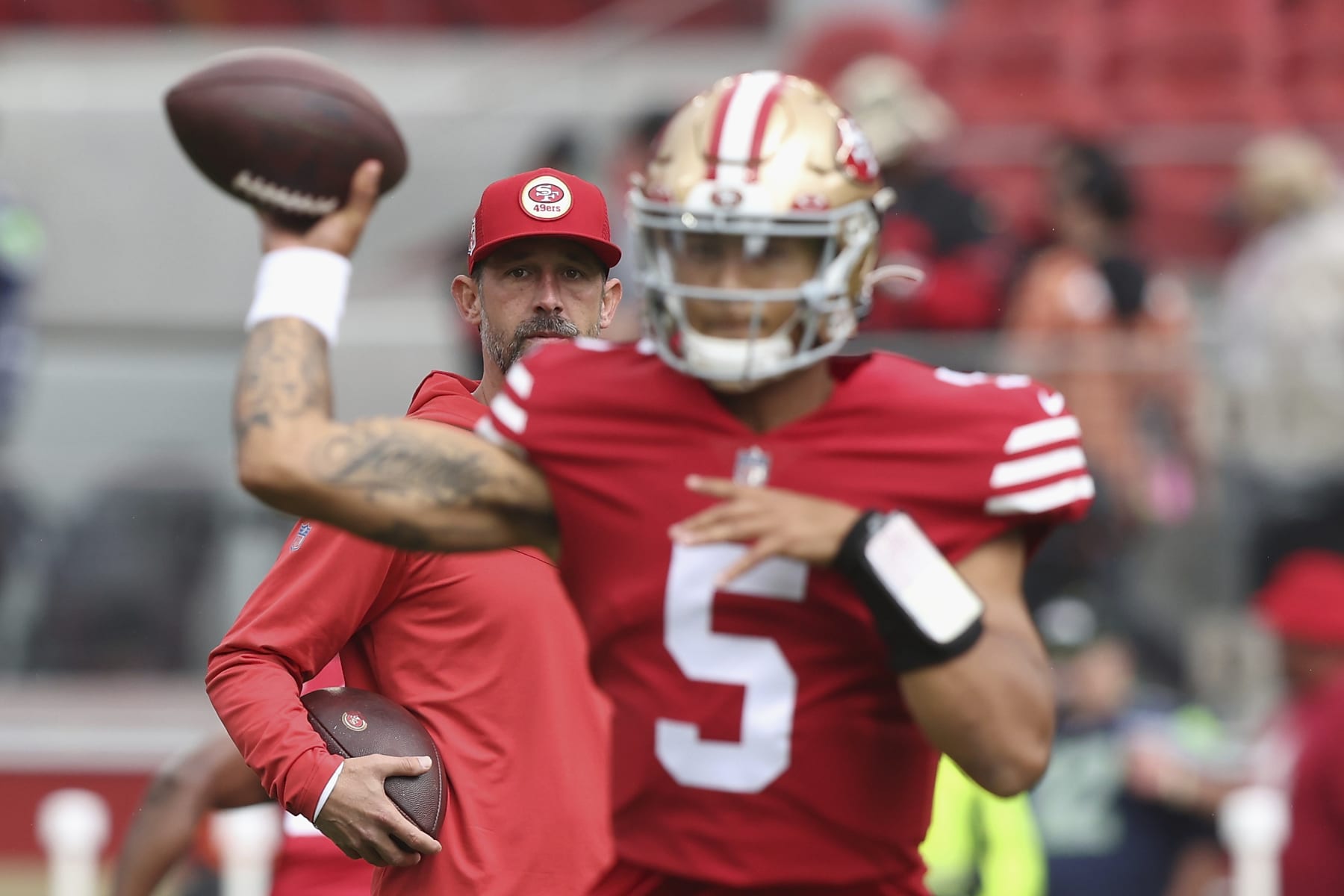 San Francisco 49ers head coach Kyle Shanahan looks on as San Francisco 49ers quarterback Trey Lance (5) warms up before an NFL football game against the Seattle Seahawks, Sunday, Sept. 18, 2022 in Santa Clara, Calif. (AP Photo/Lachlan Cunningham)