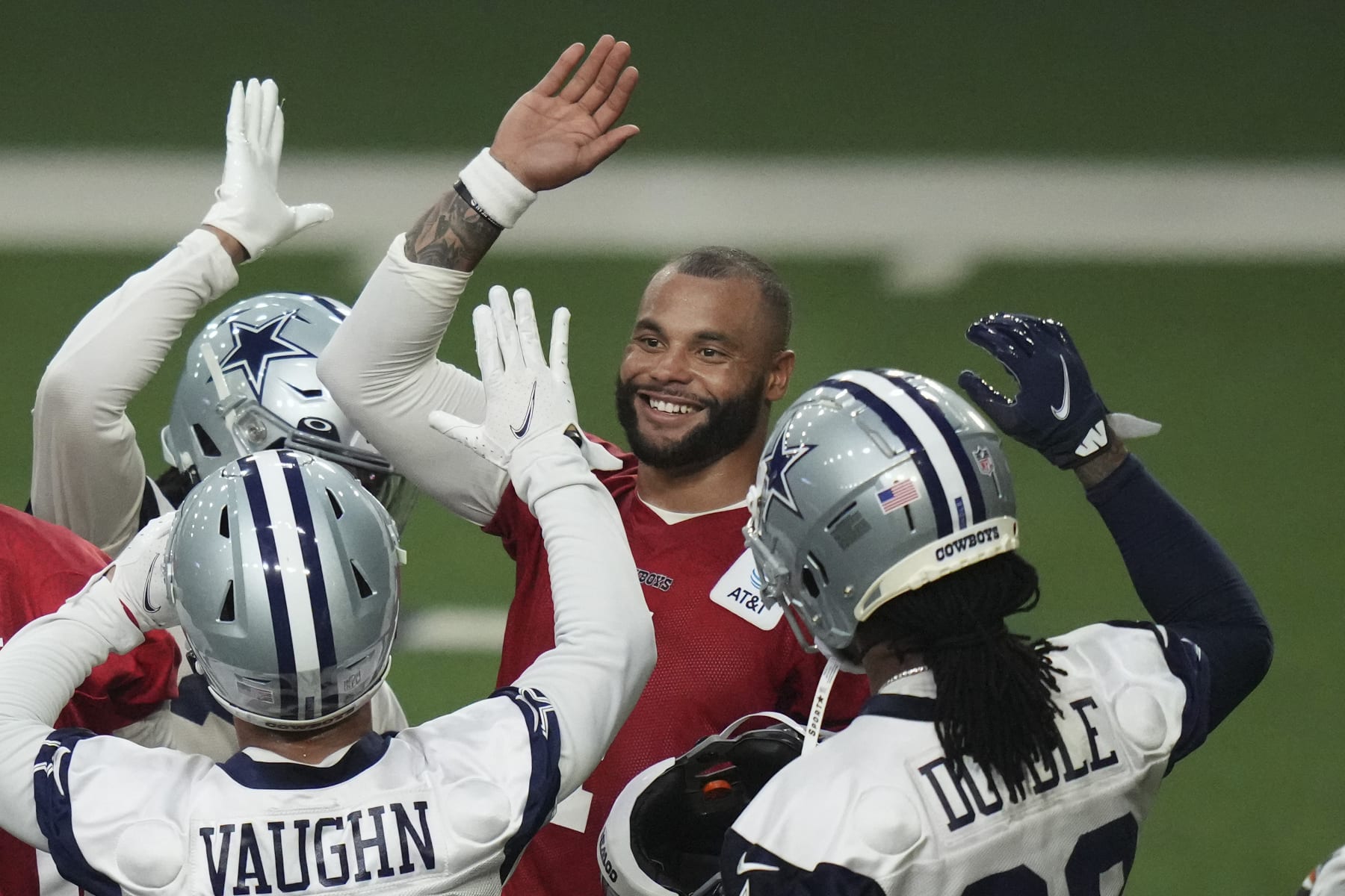 Dallas Cowboys quarterback Dak Prescott, center, high fives running backs Rico Dowdle (23), Deuce Vaughn and other teammates during NFL football practice in Frisco, Texas, Thursday, June 1, 2023. (AP Photo/LM Otero)