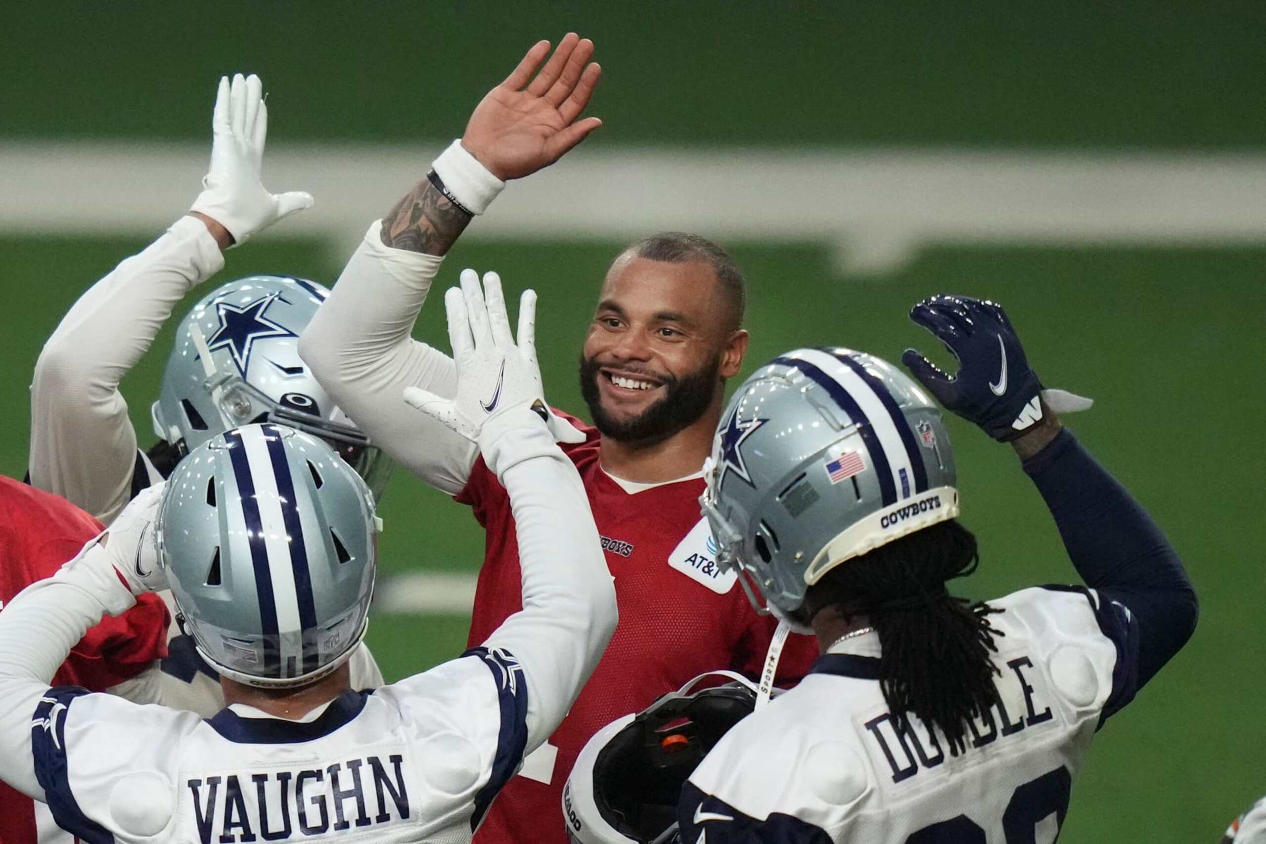 Dallas Cowboys quarterback Dak Prescott, center, high fives running backs Rico Dowdle (23), Deuce Vaughn and other teammates during NFL football practice in Frisco, Texas, Thursday, June 1, 2023. (AP Photo/LM Otero)