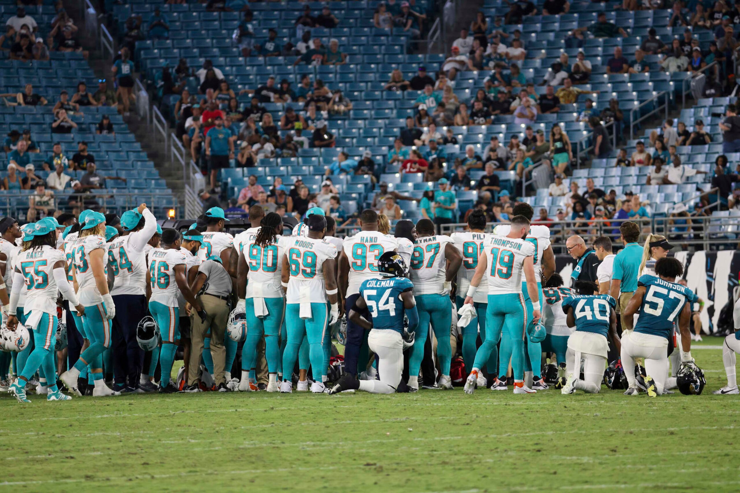 Players gather on the field after an injury to Miami Dolphins wide receiver Daewood Davis during the second half of an NFL preseason football game against the Jacksonville Jaguars, Saturday, Aug. 26, 2023, in Jacksonville, Fla. (AP Photo/Alex Menendez)