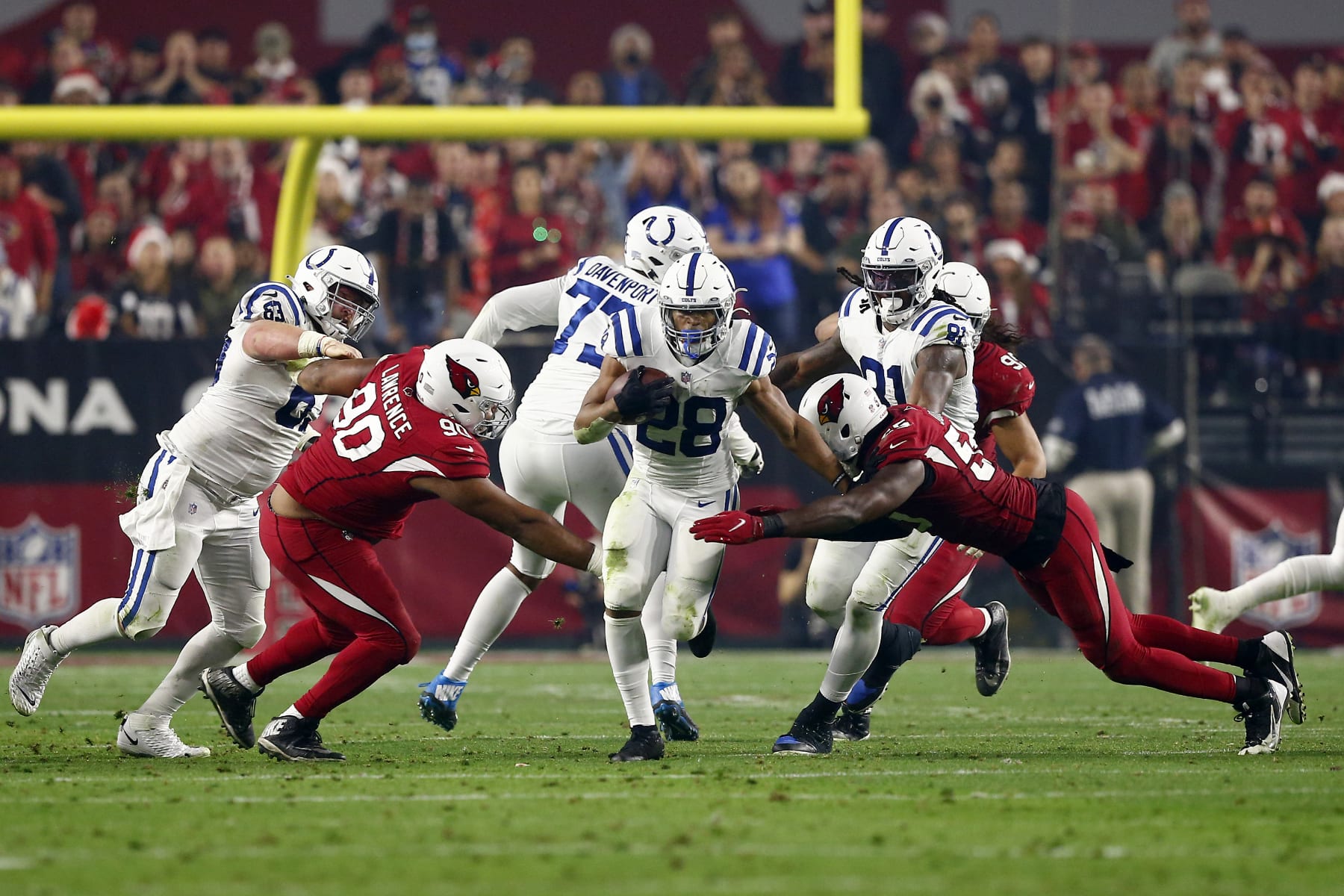 GLENDALE, AZ - DECEMBER 25: Indianapolis Colts Running Back Jonathan Taylor (28) breaks through Arizona Cardinals Nose Tackle Rashard Lawrence (90) and Arizona Cardinals Linebacker Chandler Jones (55) during an NFL game between the Indianapolis Colts and the Arizona Cardinals on December 25, 2021 at State Farm Stadium, in Glendale AZ. (Photo by Jeffrey Brown/Icon Sportswire via Getty Images)