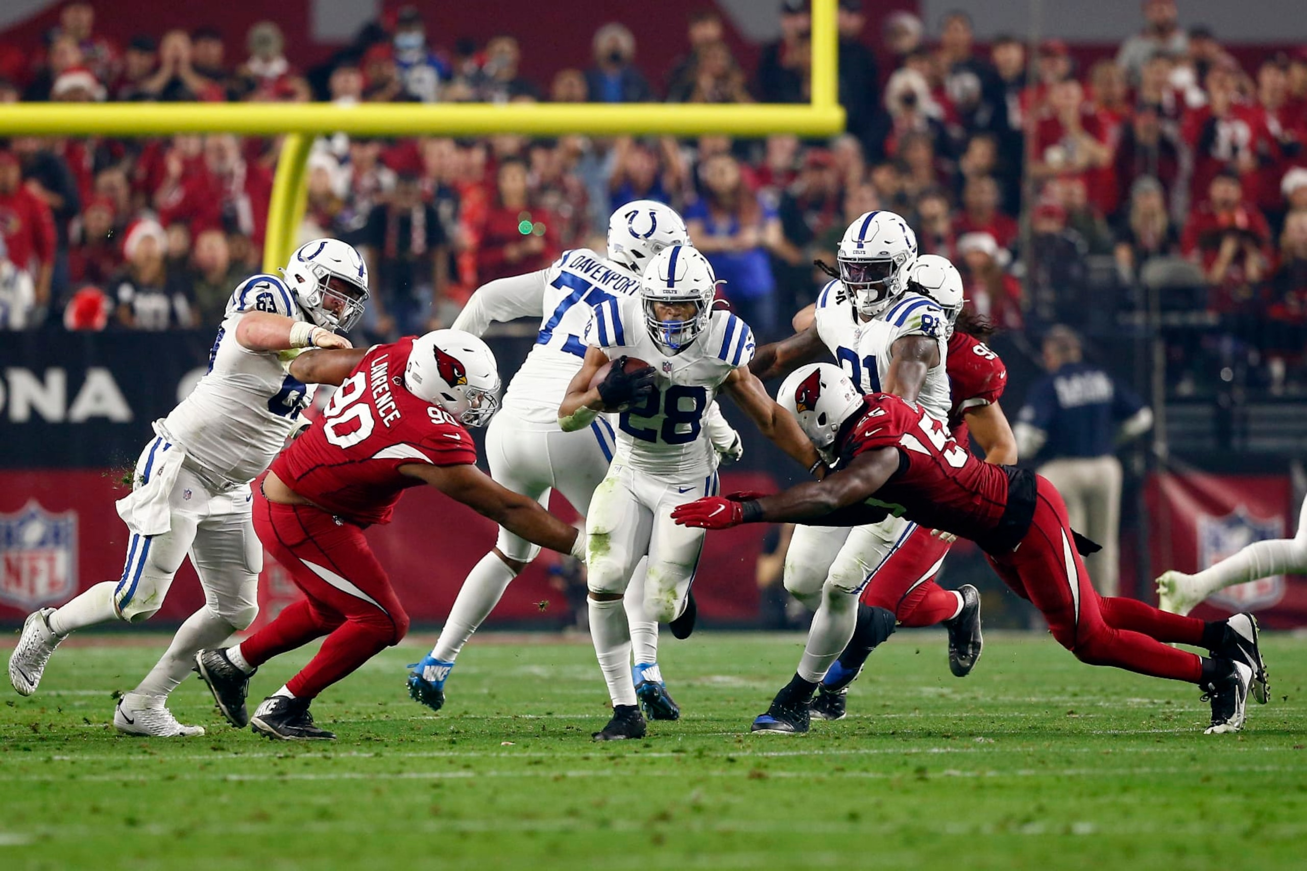 GLENDALE, AZ - DECEMBER 25: Indianapolis Colts Running Back Jonathan Taylor (28) breaks through Arizona Cardinals Nose Tackle Rashard Lawrence (90) and Arizona Cardinals Linebacker Chandler Jones (55) during an NFL game between the Indianapolis Colts and the Arizona Cardinals on December 25, 2021 at State Farm Stadium, in Glendale AZ. (Photo by Jeffrey Brown/Icon Sportswire via Getty Images)