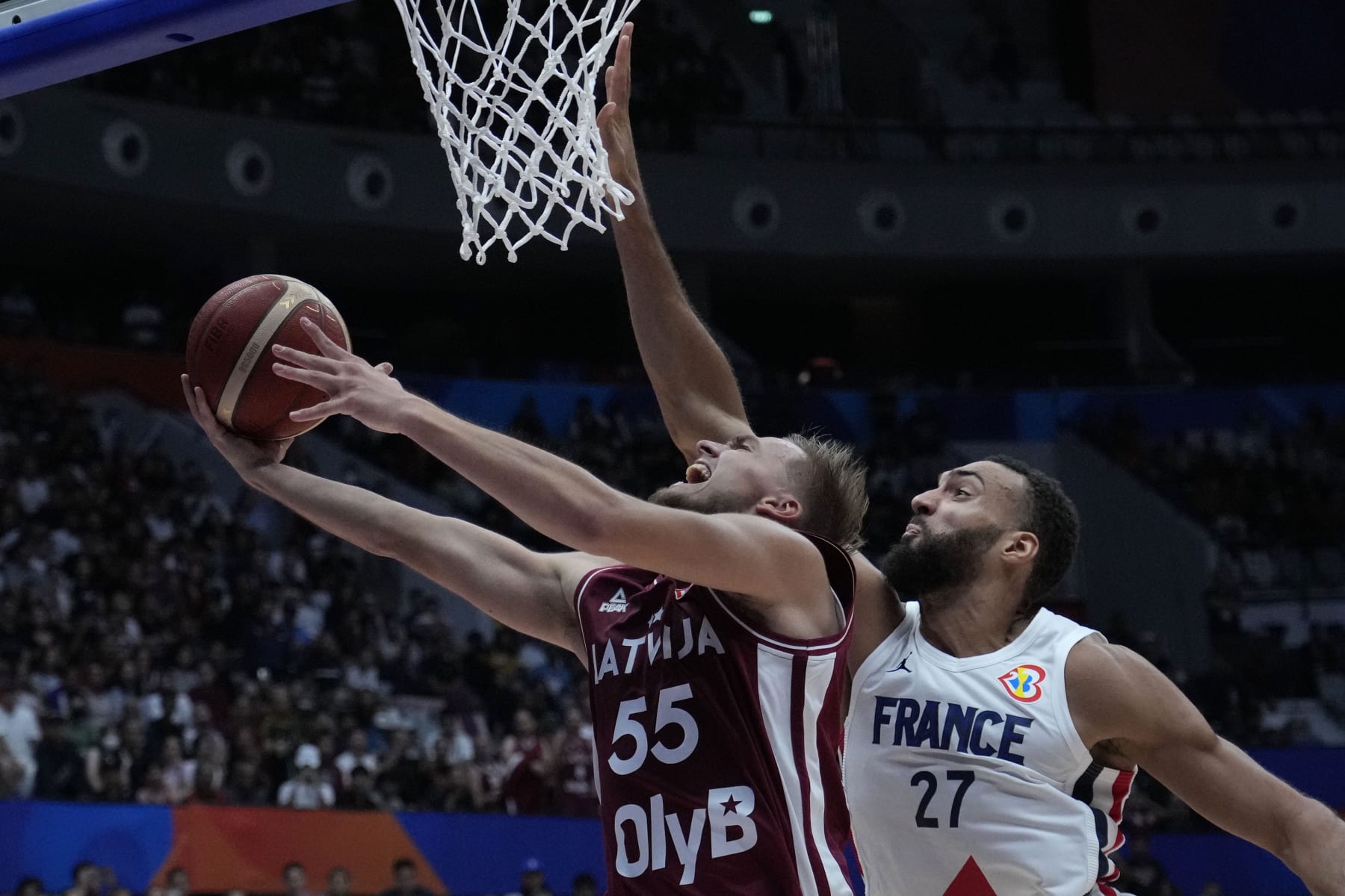 Latvia guard Arturs Zagars (55) shoots against France center Rudy Gobert (27) during the Basketball World Cup group H match between France and Latvia at the Indonesia Arena stadium in Jakarta, Indonesia, Sunday, Aug. 27, 2023. (AP Photo/Achmad Ibrahim)