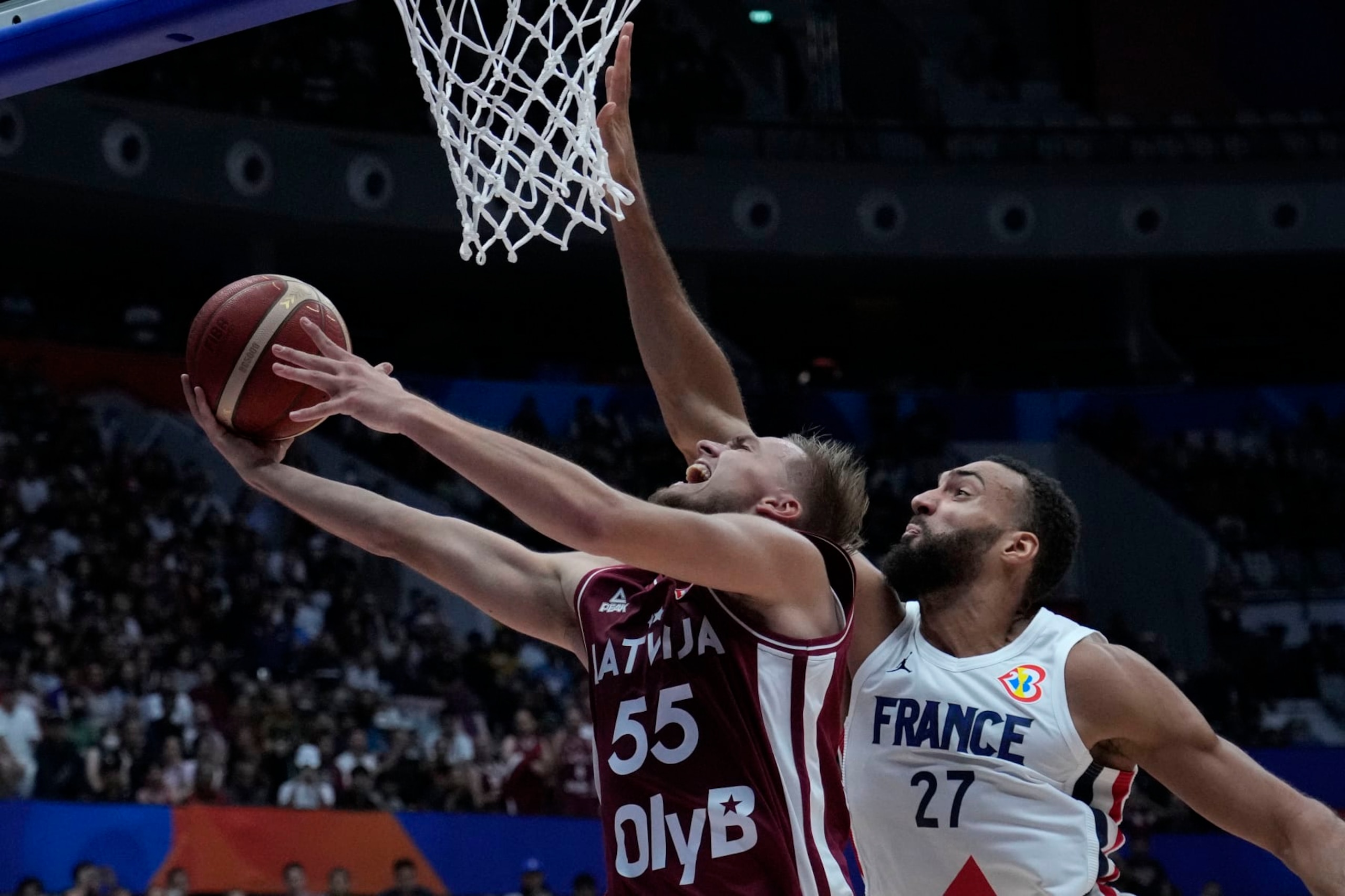 Latvia guard Arturs Zagars (55) shoots against France center Rudy Gobert (27) during the Basketball World Cup group H match between France and Latvia at the Indonesia Arena stadium in Jakarta, Indonesia, Sunday, Aug. 27, 2023. (AP Photo/Achmad Ibrahim)