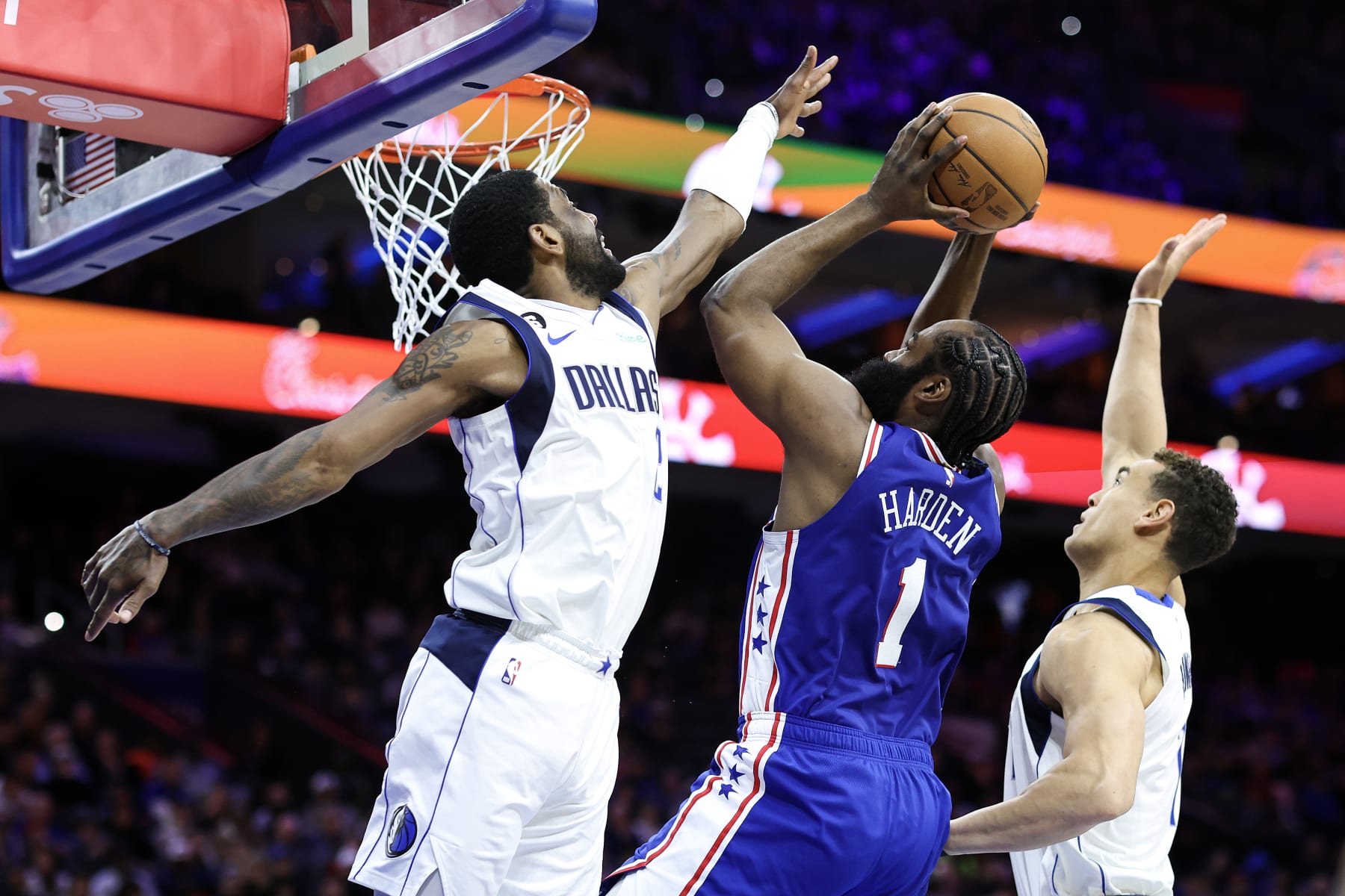 PHILADELPHIA, PENNSYLVANIA - MARCH 29: James Harden #1 of the Philadelphia 76ers shoots a lay up between Kyrie Irving #2 and Dwight Powell #7 of the Dallas Mavericks during the second quarter at Wells Fargo Center on March 29, 2023 in Philadelphia, Pennsylvania. NOTE TO USER: User expressly acknowledges and agrees that, by downloading and or using this photograph, User is consenting to the terms and conditions of the Getty Images License Agreement. (Photo by Tim Nwachukwu/Getty Images)