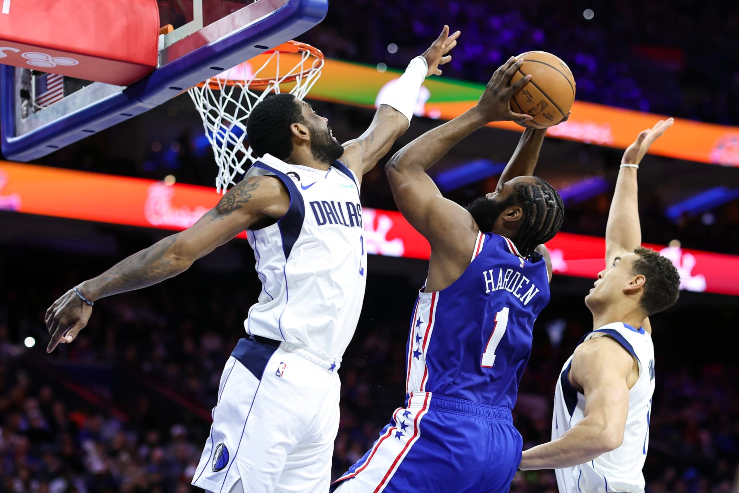 PHILADELPHIA, PENNSYLVANIA - MARCH 29: James Harden #1 of the Philadelphia 76ers shoots a lay up between Kyrie Irving #2 and Dwight Powell #7 of the Dallas Mavericks during the second quarter at Wells Fargo Center on March 29, 2023 in Philadelphia, Pennsylvania. NOTE TO USER: User expressly acknowledges and agrees that, by downloading and or using this photograph, User is consenting to the terms and conditions of the Getty Images License Agreement. (Photo by Tim Nwachukwu/Getty Images)