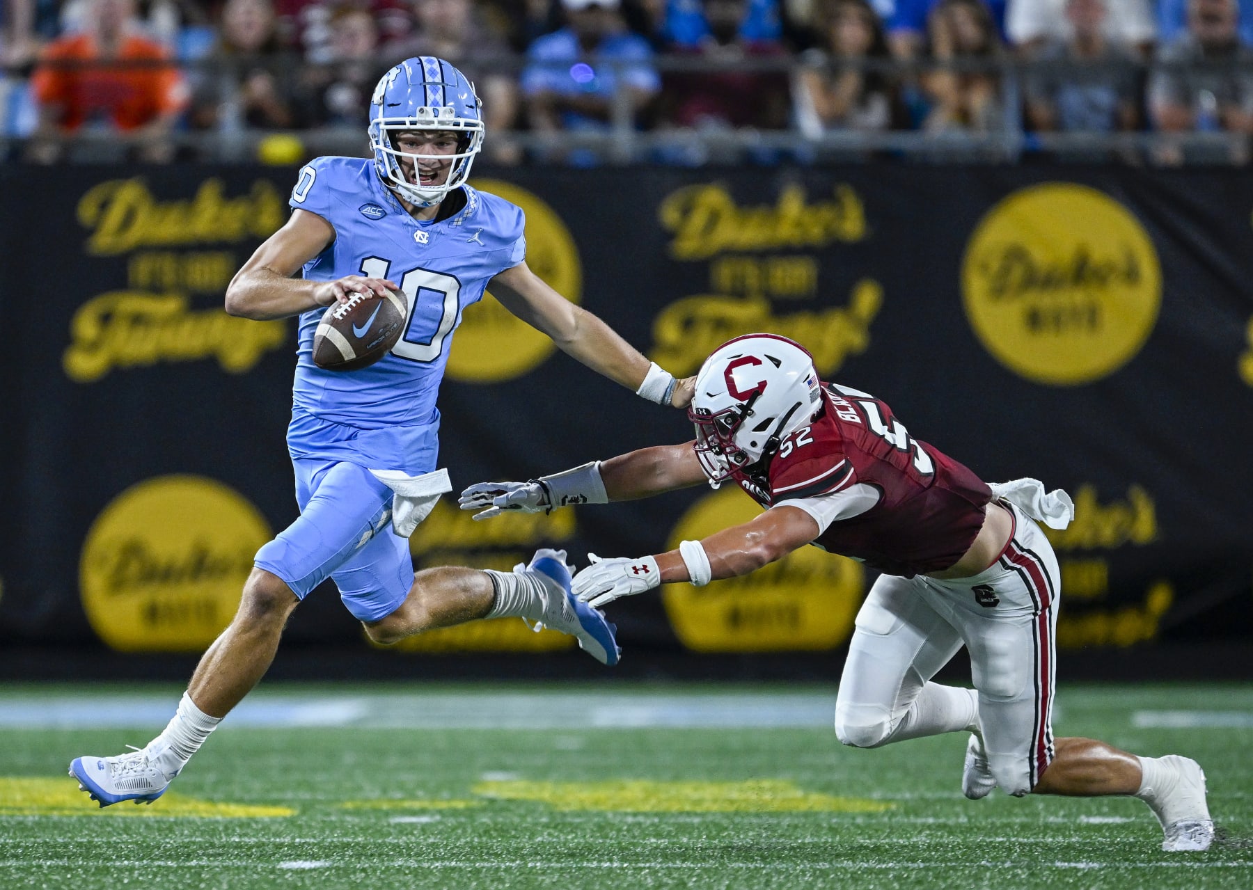 CHARLOTTE, NORTH CAROLINA - SEPTEMBER 02: Drake Maye #10 of the North Carolina Tar Heels stiff-arms Stone Blanton #52 of the South Carolina Gamecocks during the first half of the game at Bank of America Stadium on September 02, 2023 in Charlotte, North Carolina. (Photo by Grant Halverson/Getty Images)