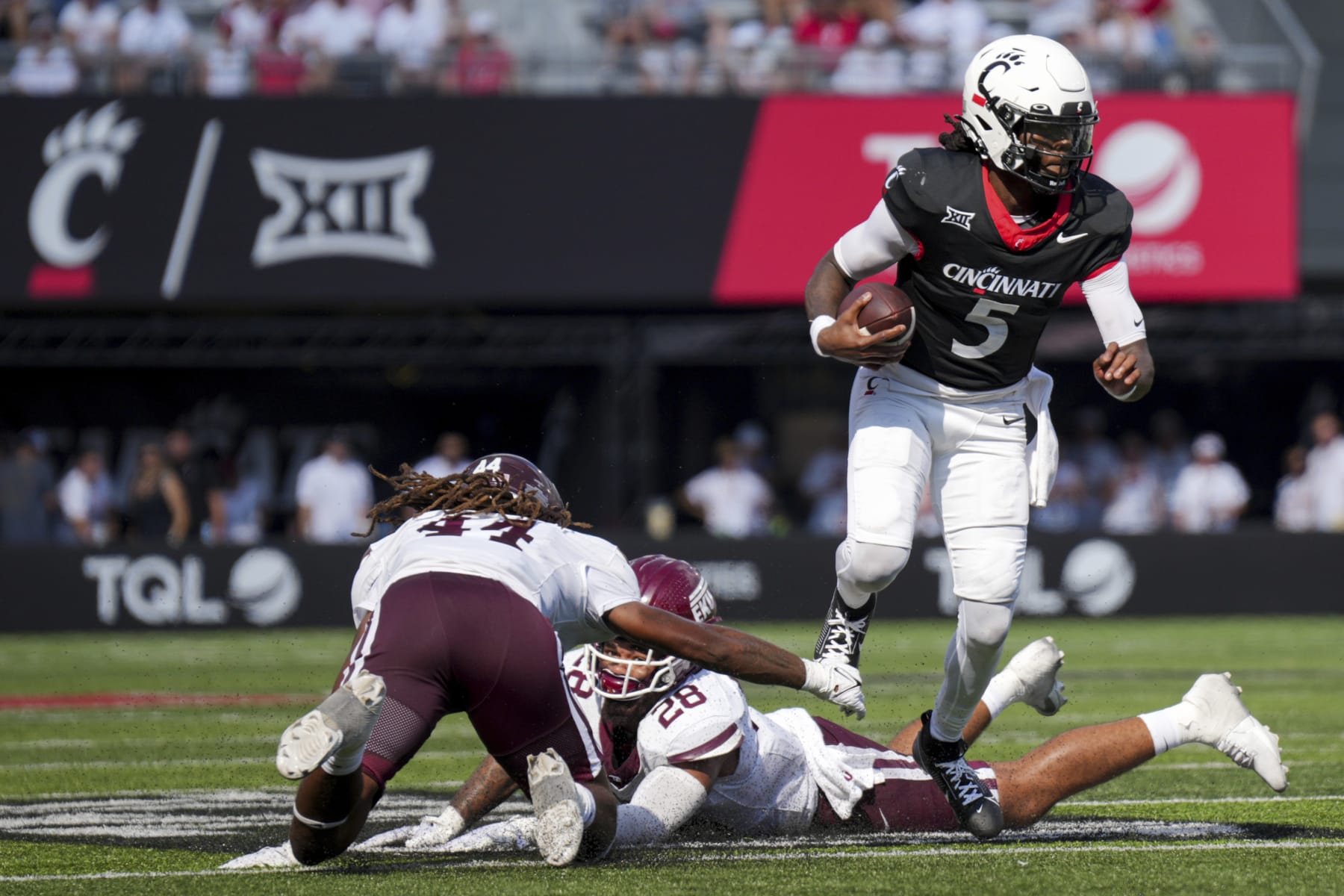 Cincinnati quarterback Emory Jones (5) carries the ball as he avoids Eastern Kentucky linebacker Jaylen Herrud, back, and linebacker Gabe Stephens, left, during the first half of an NCAA college football game, Saturday, Sept. 2, 2023, in Cincinnati. (AP Photo/Aaron Doster)