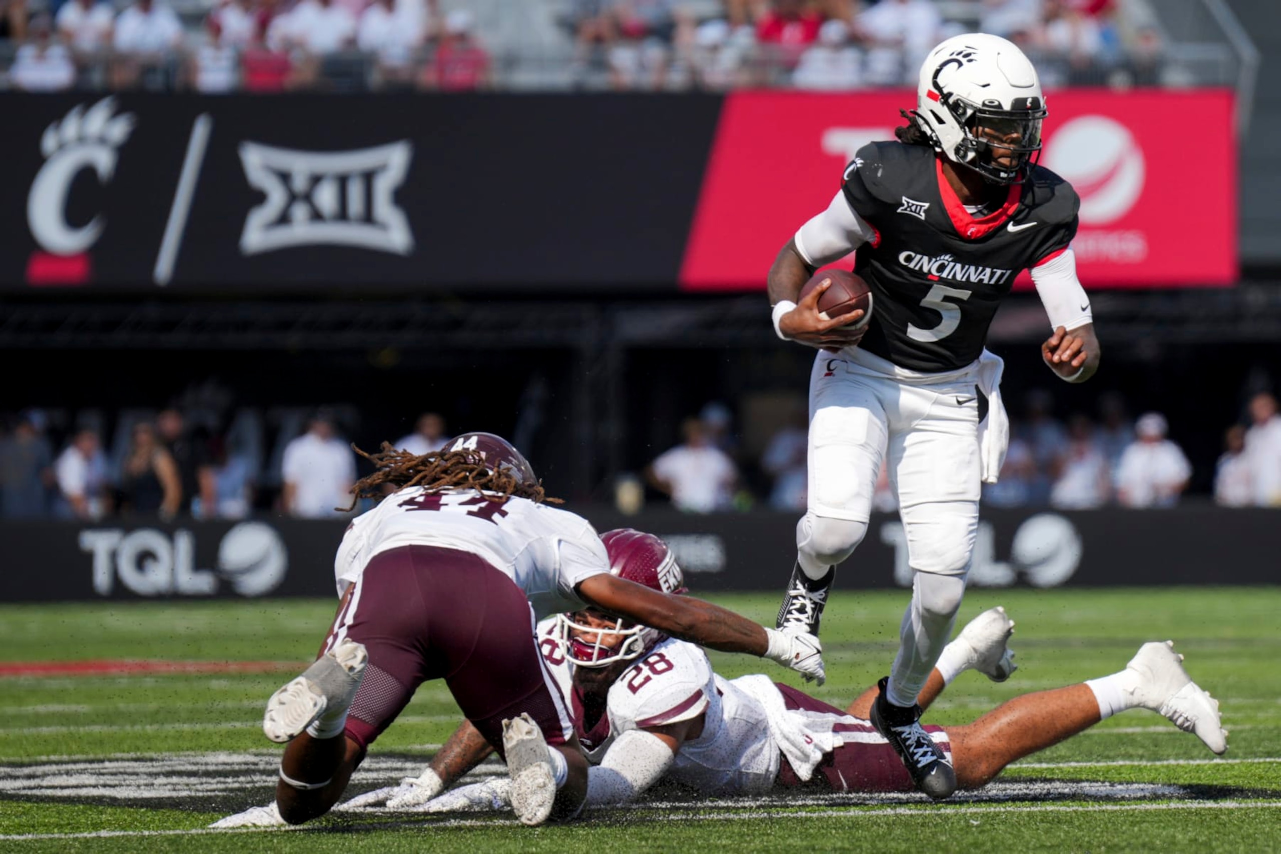 Cincinnati quarterback Emory Jones (5) carries the ball as he avoids Eastern Kentucky linebacker Jaylen Herrud, back, and linebacker Gabe Stephens, left, during the first half of an NCAA college football game, Saturday, Sept. 2, 2023, in Cincinnati. (AP Photo/Aaron Doster)